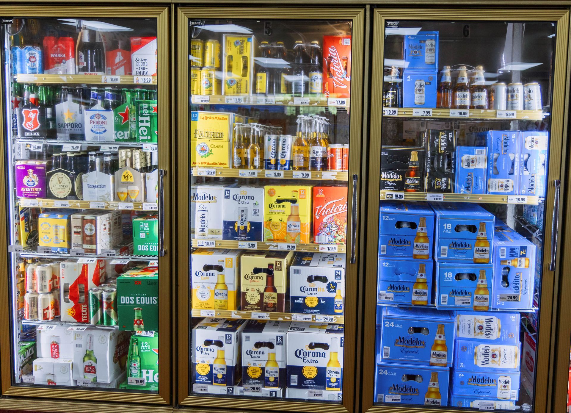 Three glass-doored coolers stocked with beer and liquor in a store, various brands and sizes.