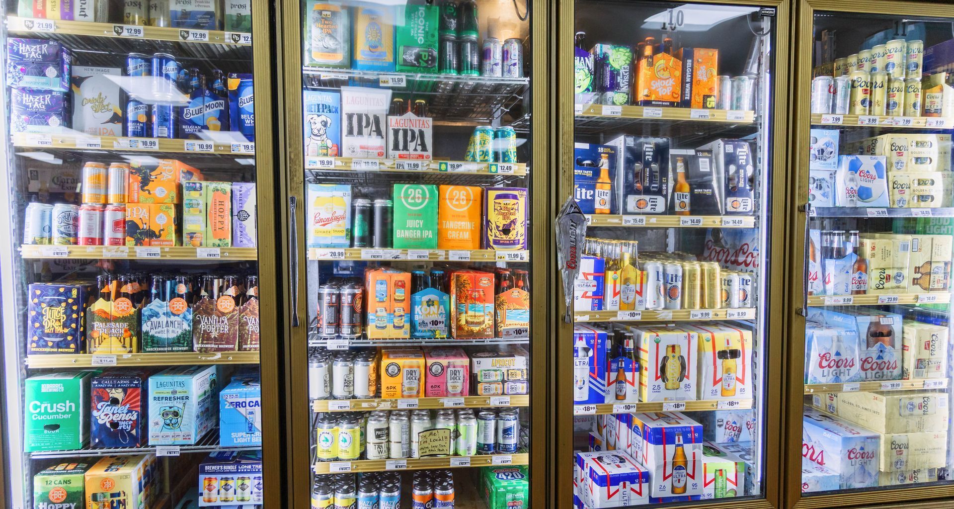 Glass door refrigerators stocked with beer cans and bottles at a store.