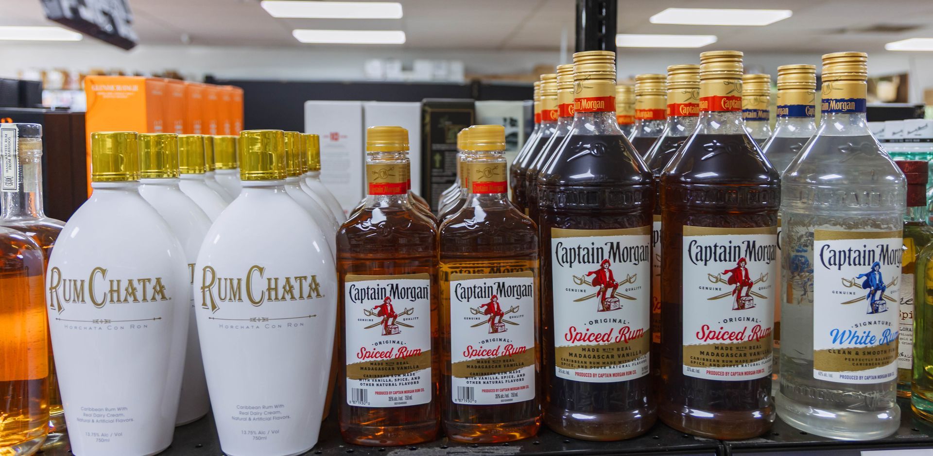 Bottles of liquor on a shelf, including RumChata and Captain Morgan rum.