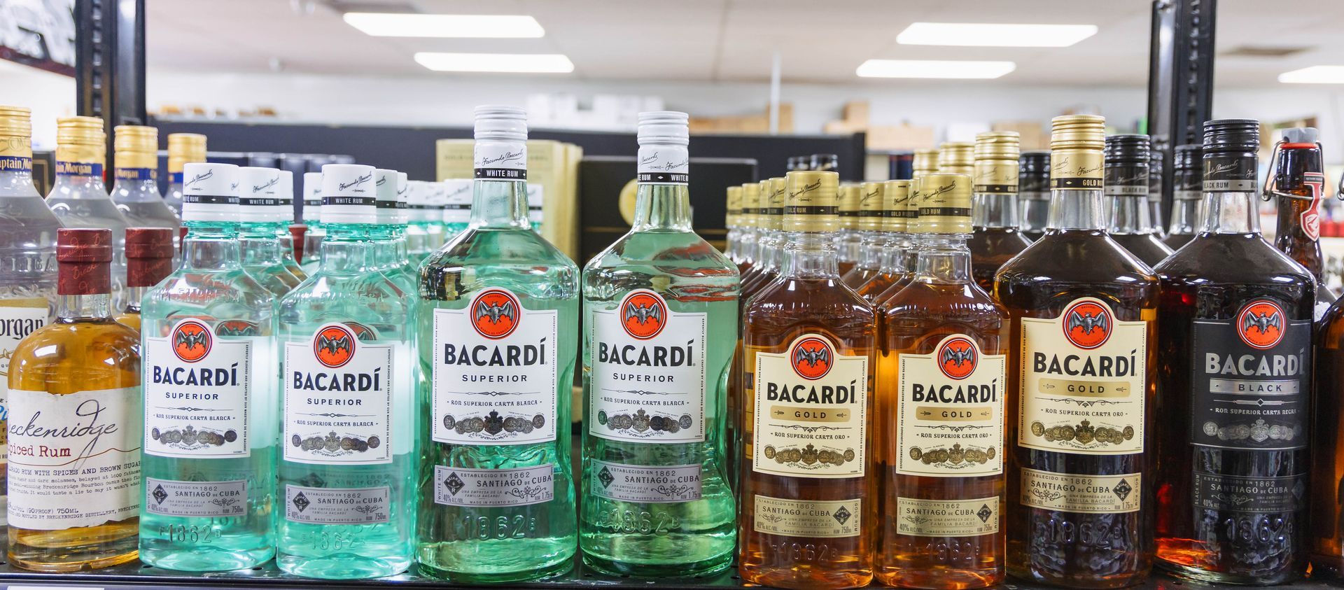 Bottles of Bacardi rum on a shelf in a liquor store.