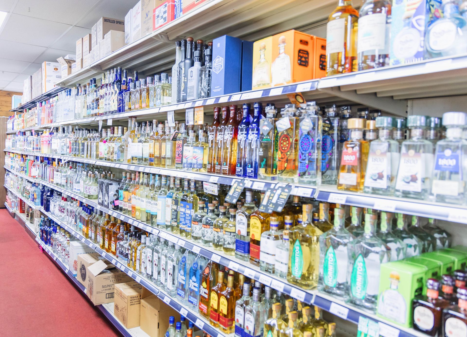 Shelves filled with bottles of liquor in a liquor store. Various brands and colors of alcohol displayed.