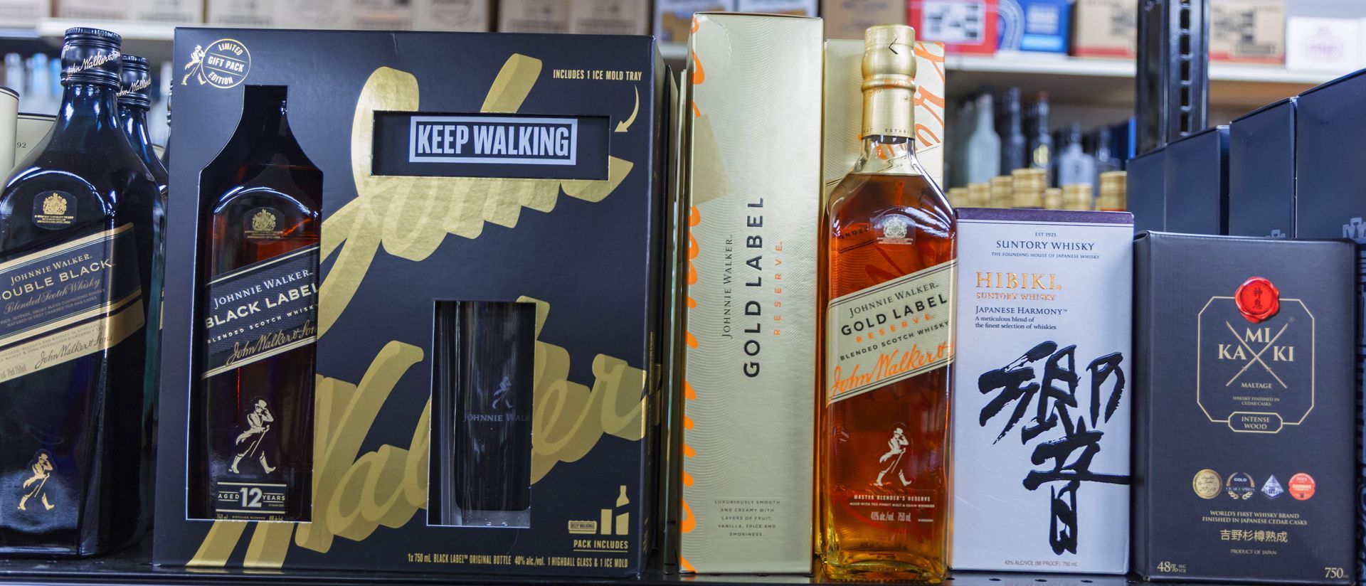 Whiskey bottles and boxes on a shelf in a store. Johnnie Walker labels are visible.