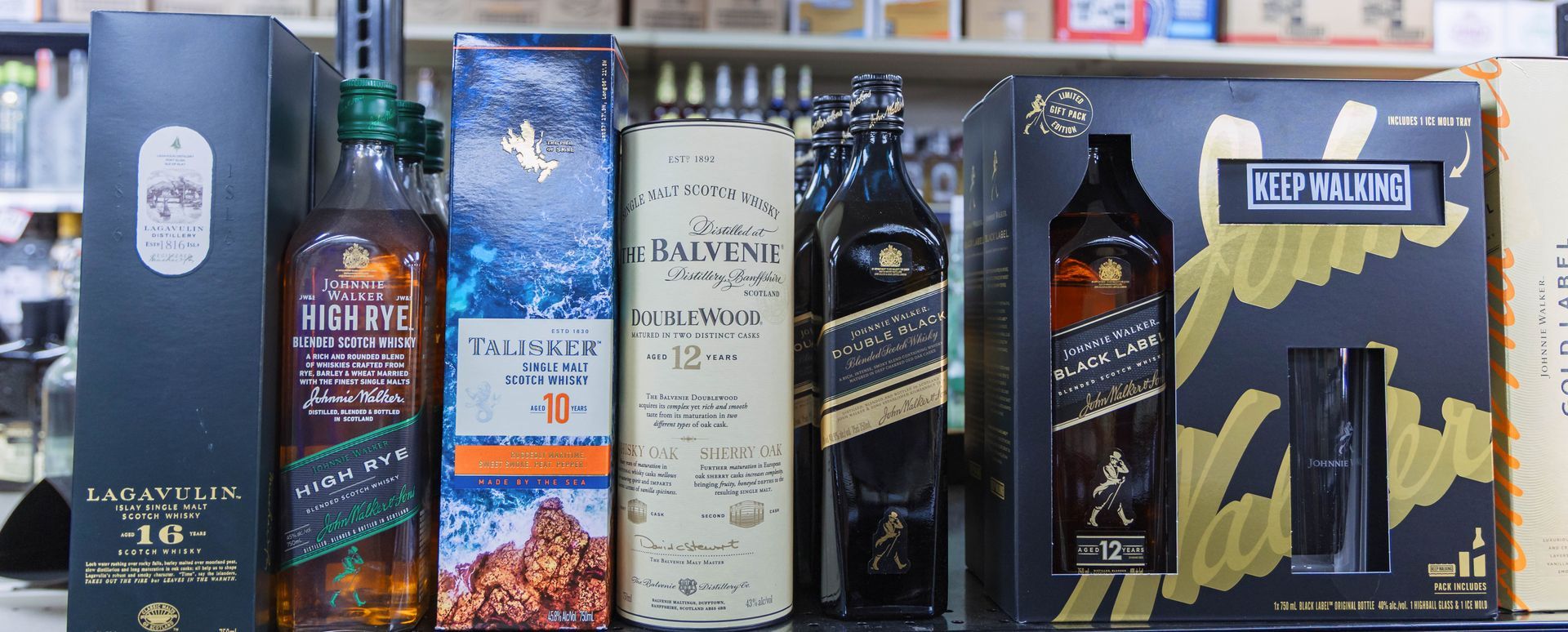 Assortment of whiskey bottles with different brands and designs on a shelf.