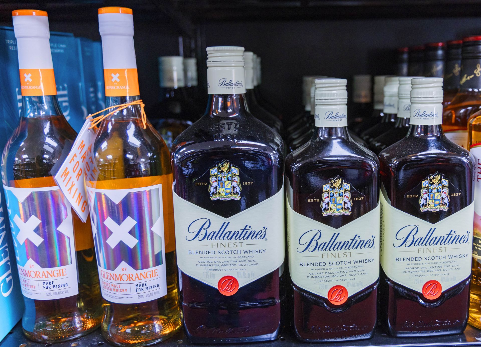 Bottles of Ballantine's Finest Scotch whisky and other alcoholic beverages on a store shelf.