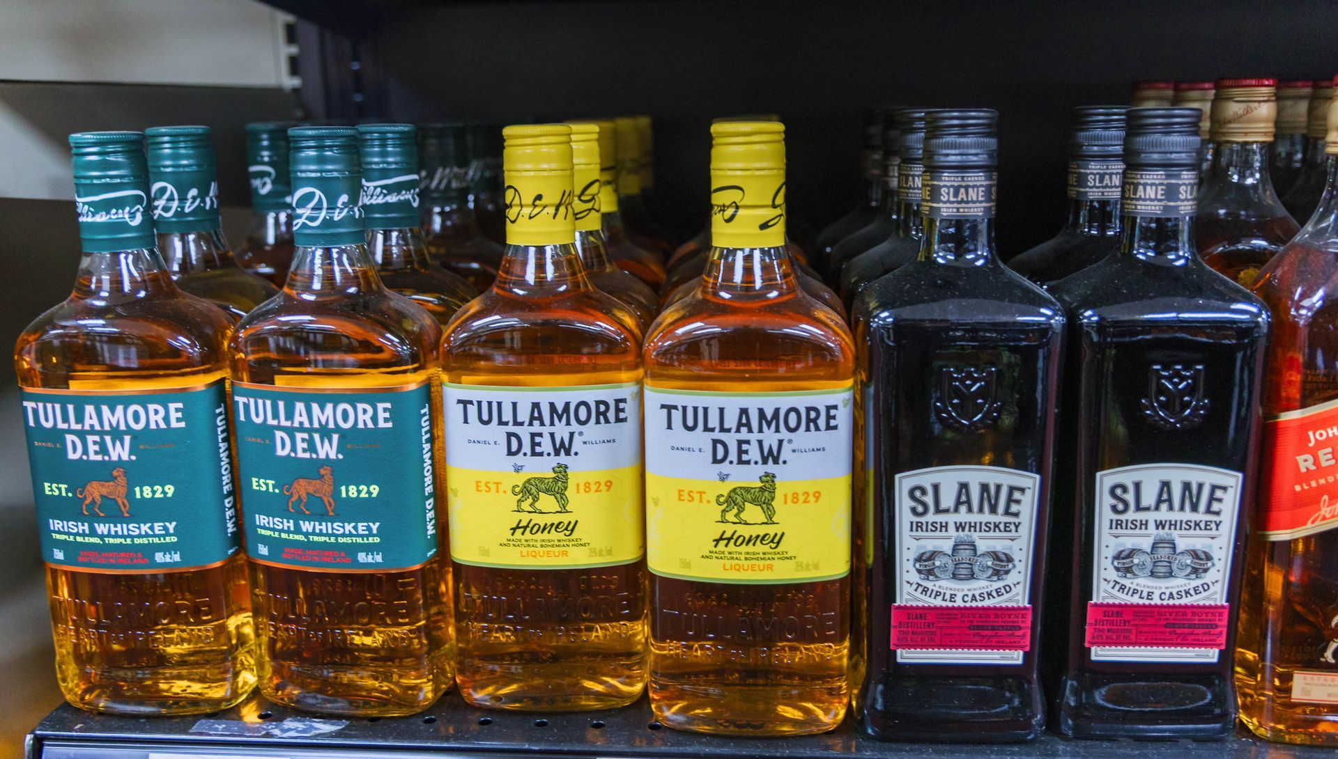 Bottles of Irish whiskey, including Tullamore D.E.W. and Slane, displayed on a store shelf.