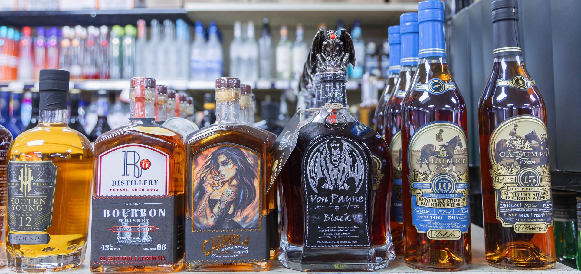 Liquor bottles in a store, varying brands and labels, brown and clear liquid, several with ornate designs.