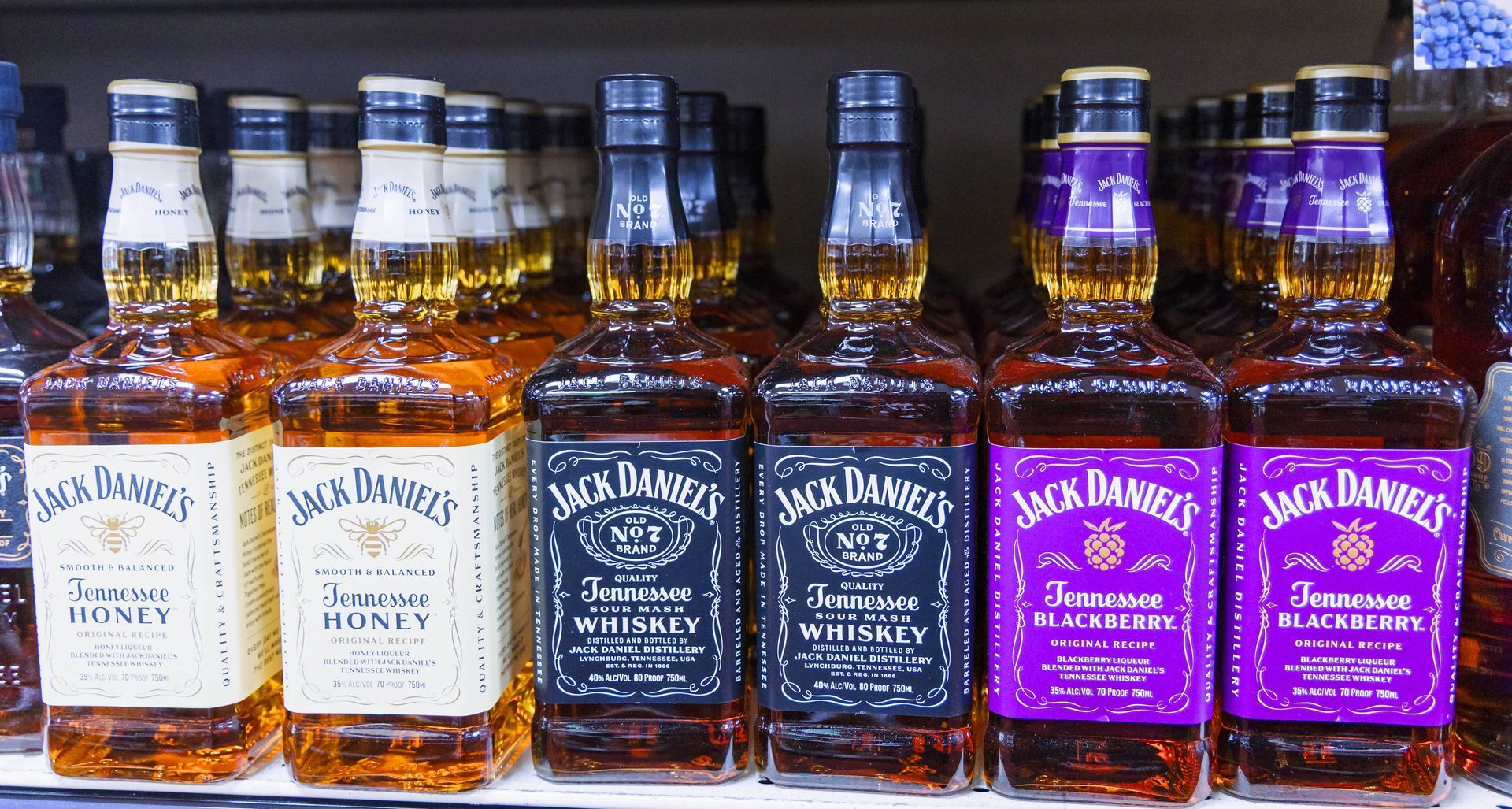 Bottles of Jack Daniel's whiskey in a store, including Honey, Tennessee Whiskey, and Blackberry flavors.