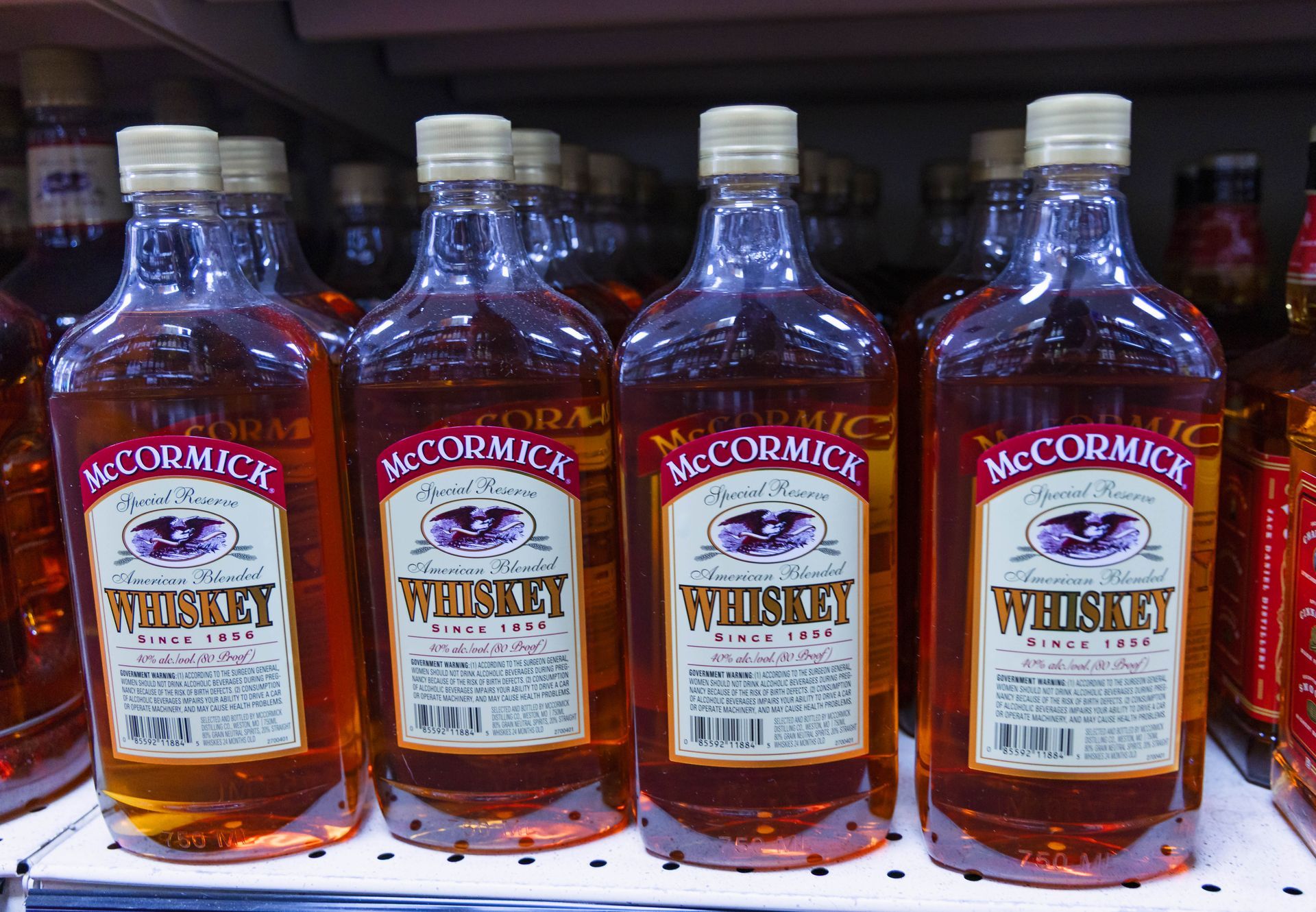 Bottles of McCormick whiskey on a shelf in a store. The bottles are amber with a white label.