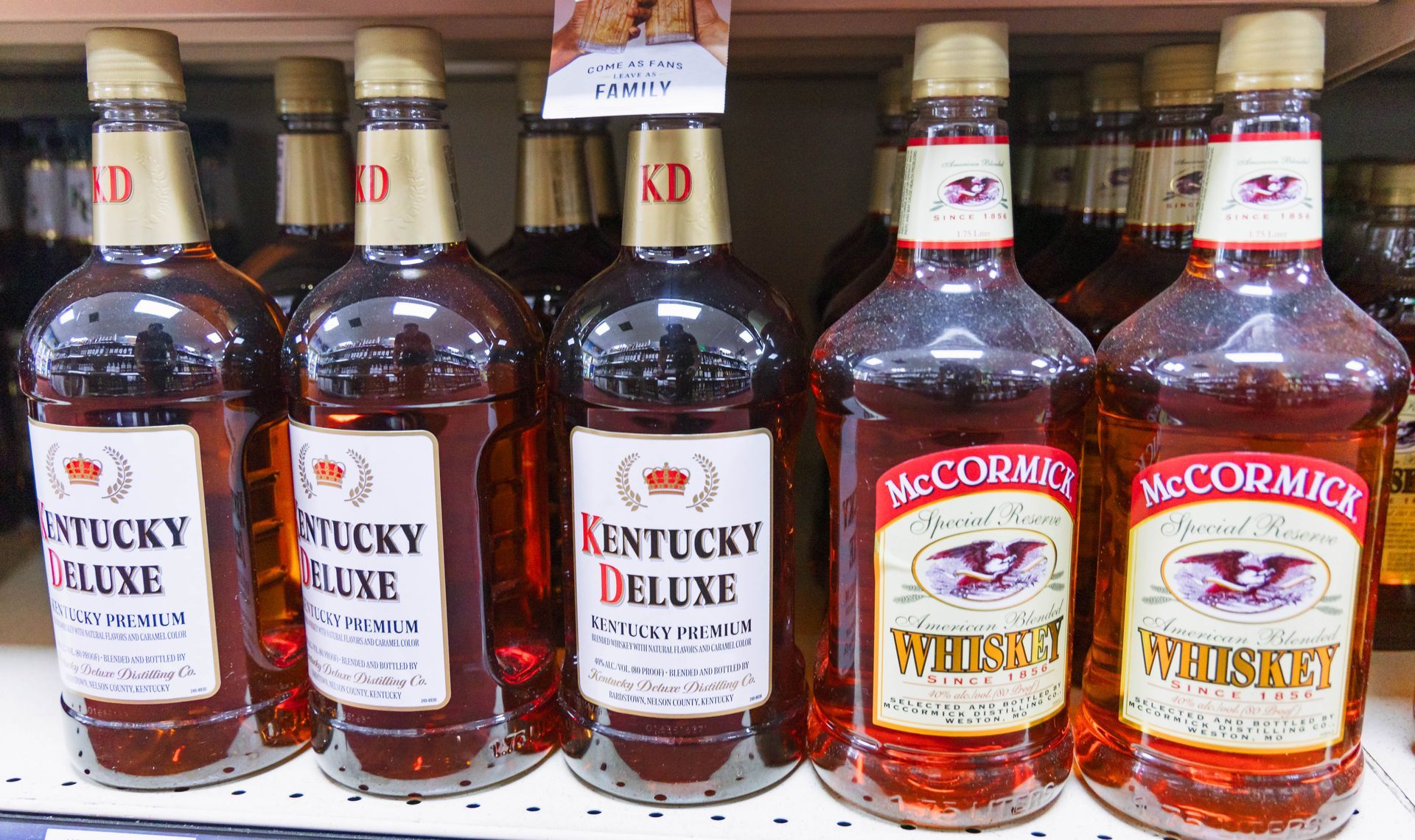 Bottles of Kentucky Deluxe and McCormick whiskey on a shelf.