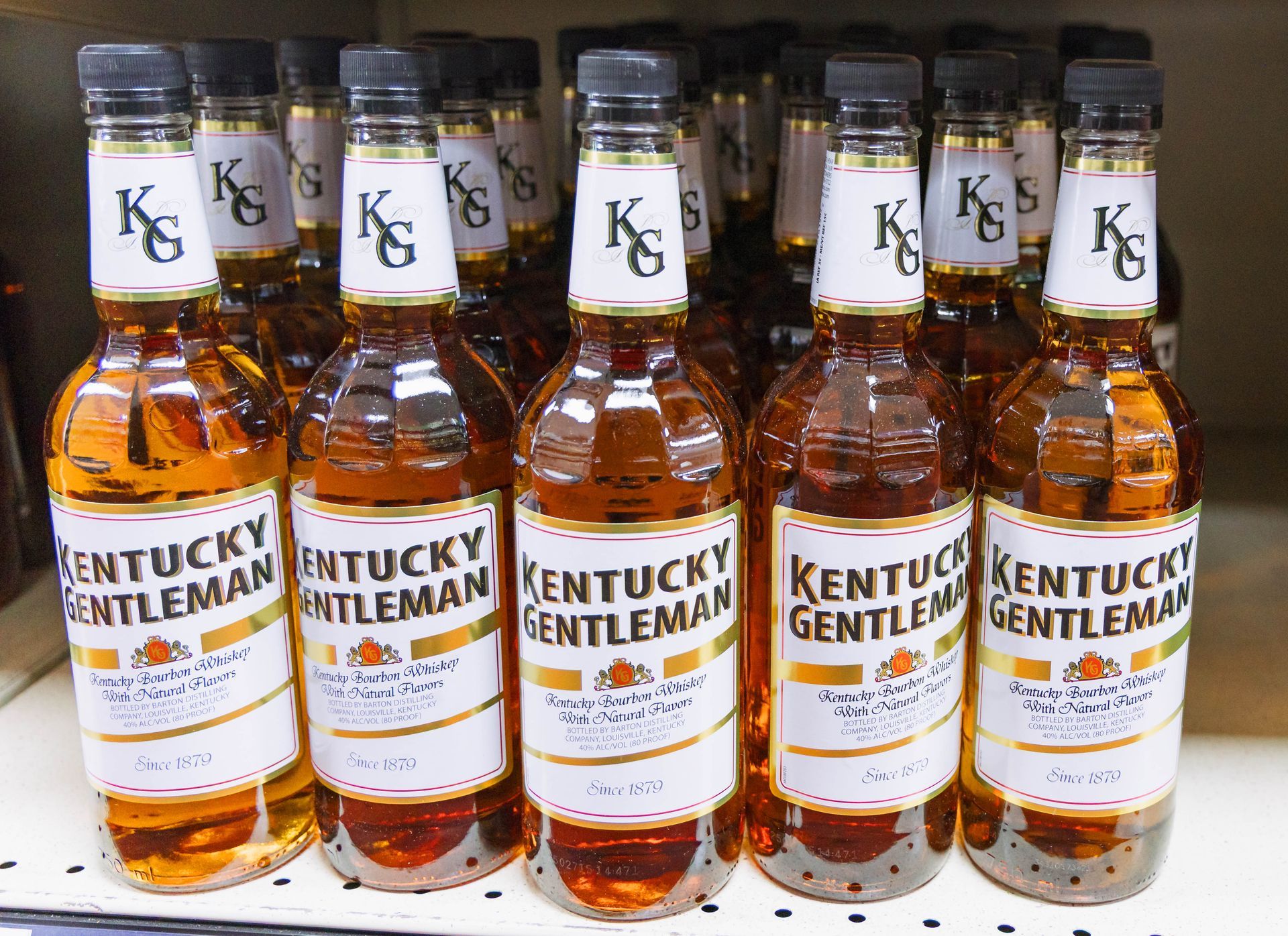 Bottles of Kentucky Gentleman bourbon displayed on a store shelf. Brown liquor in glass bottles, labels with gold accents.