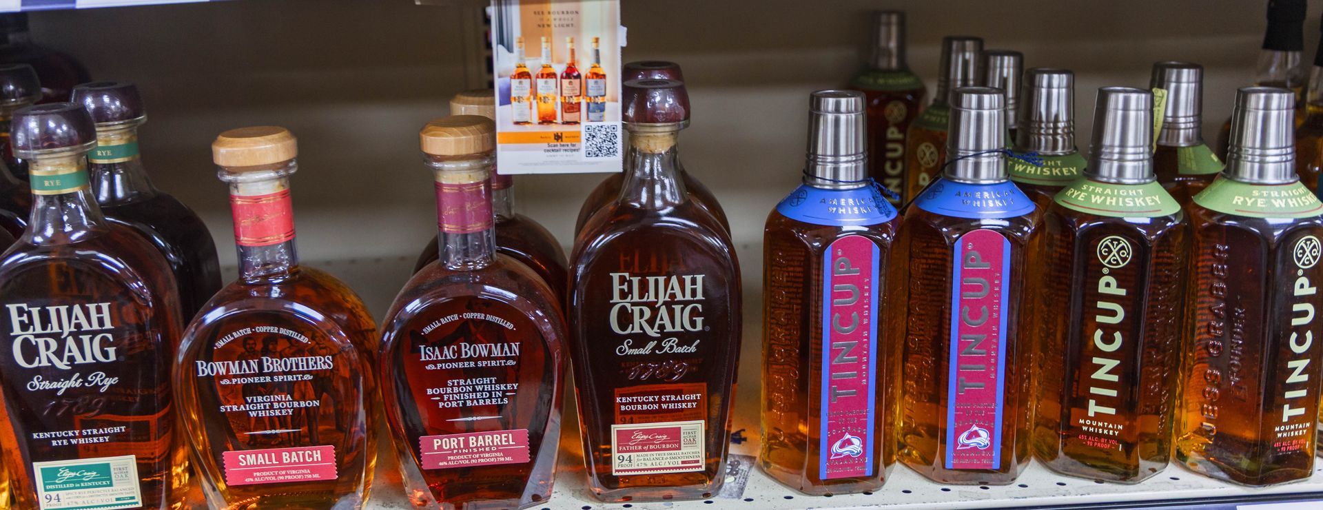 Bottles of bourbon on a store shelf, with various labels, some blue, green, and red.