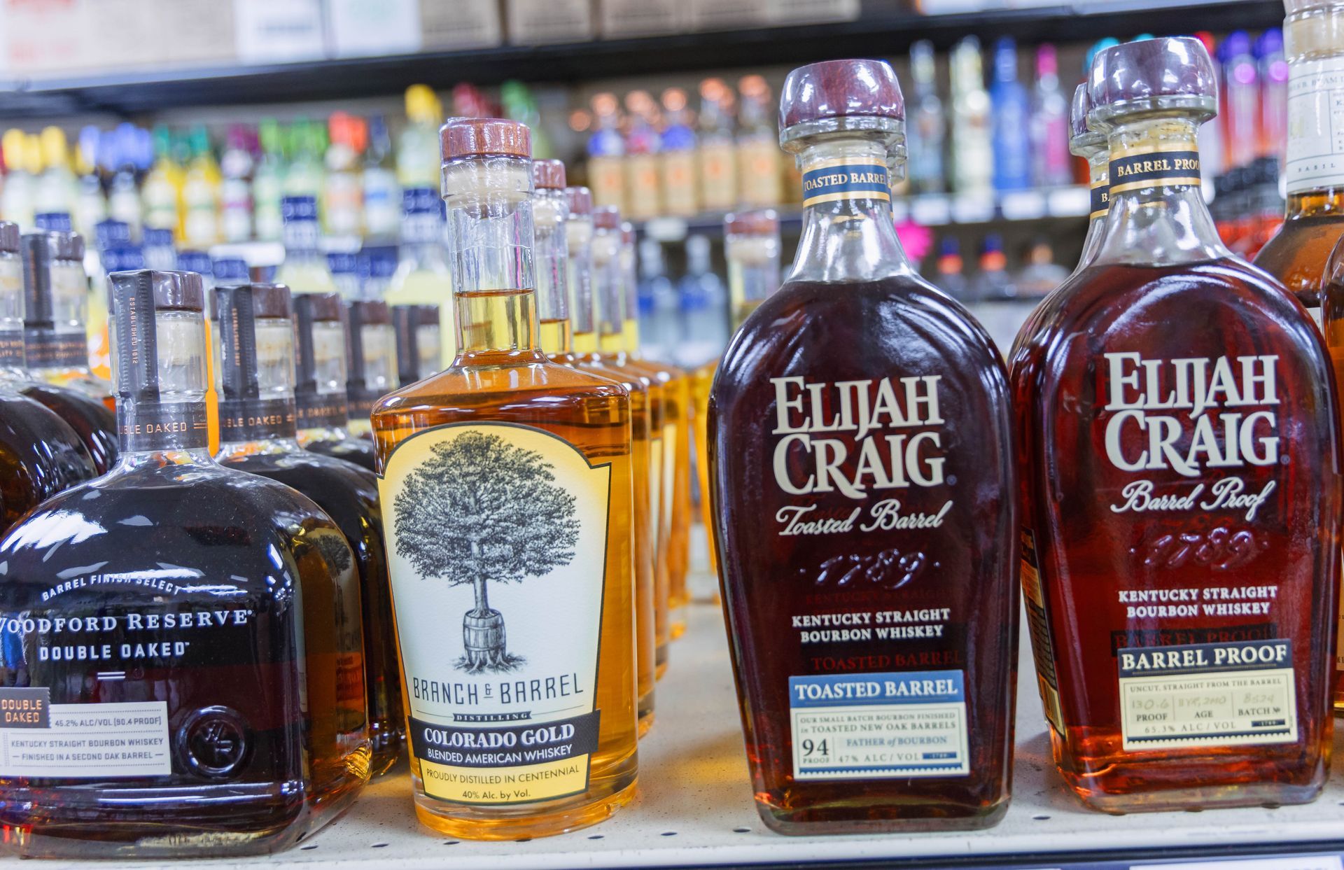 Bottles of bourbon whiskey on a shelf in a liquor store. Featuring Elijah Craig and other brands.