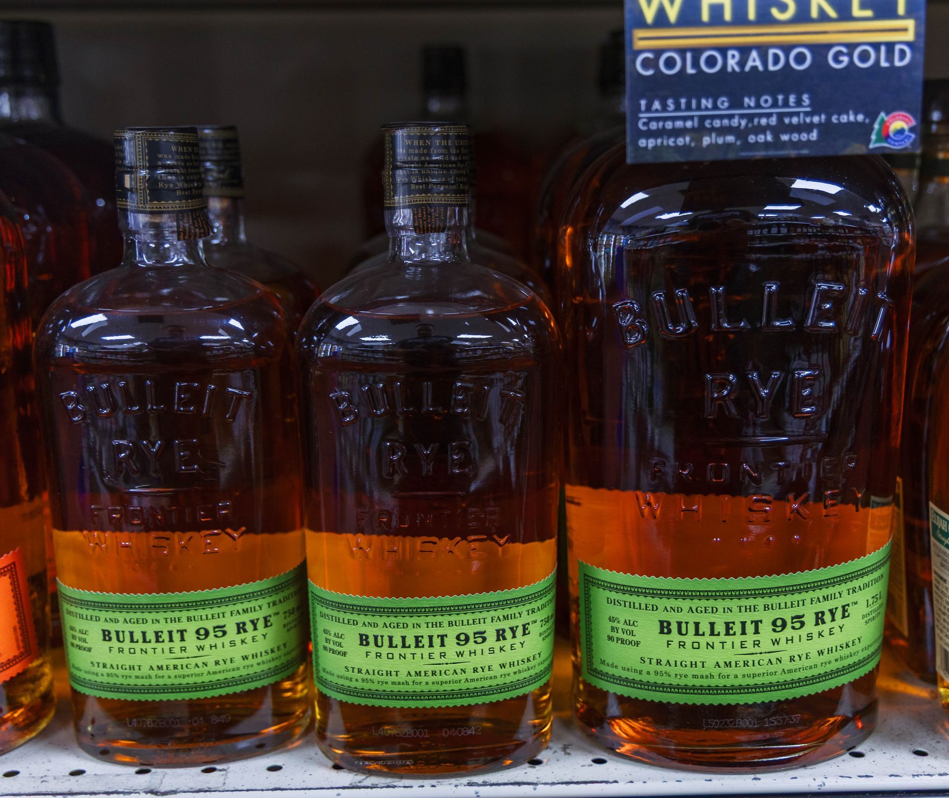Bottles of Bulleit 95 Rye whiskey on a shelf, with a tasting notes sign.