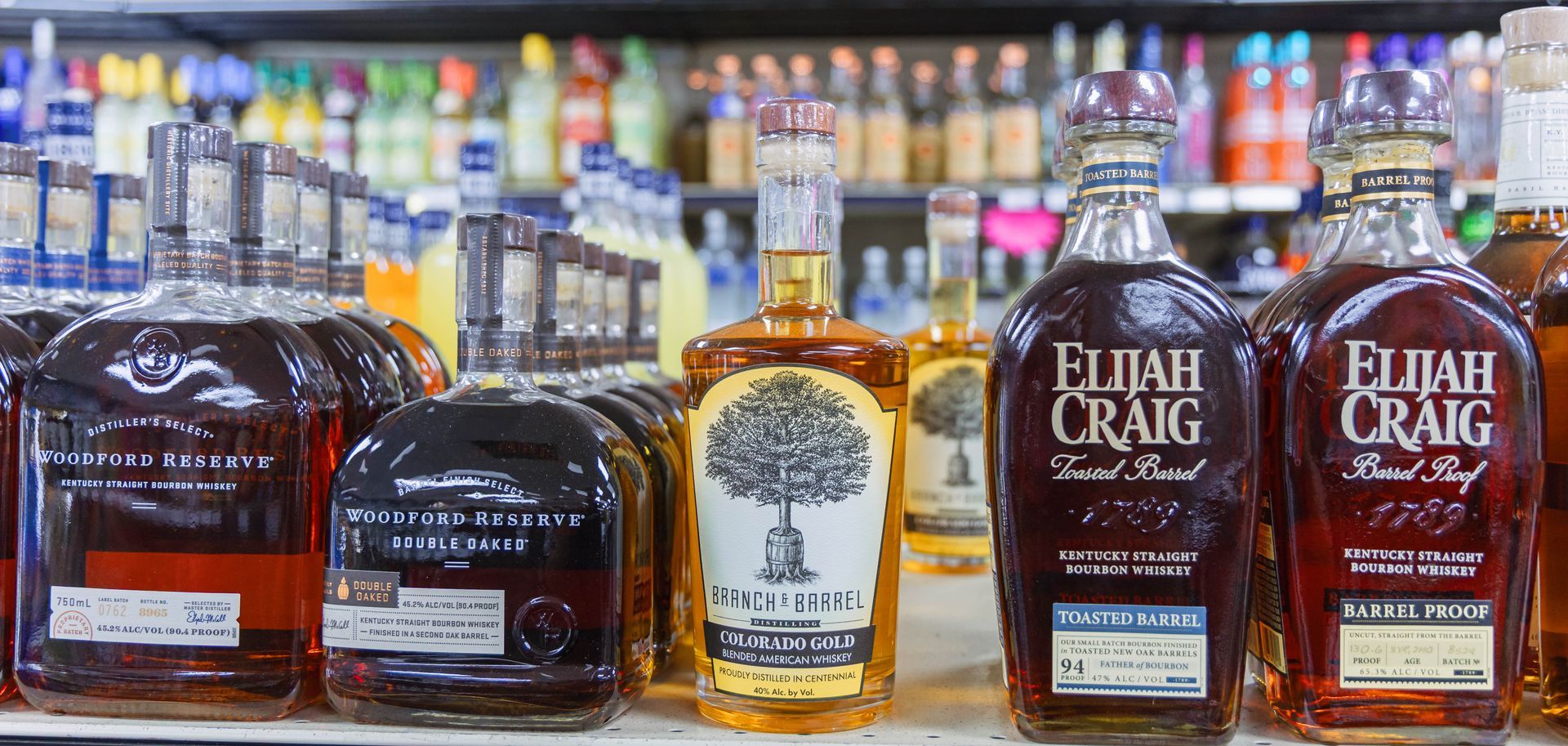 Bourbon bottles on a shelf in a liquor store, including Elijah Craig Barrel Proof.
