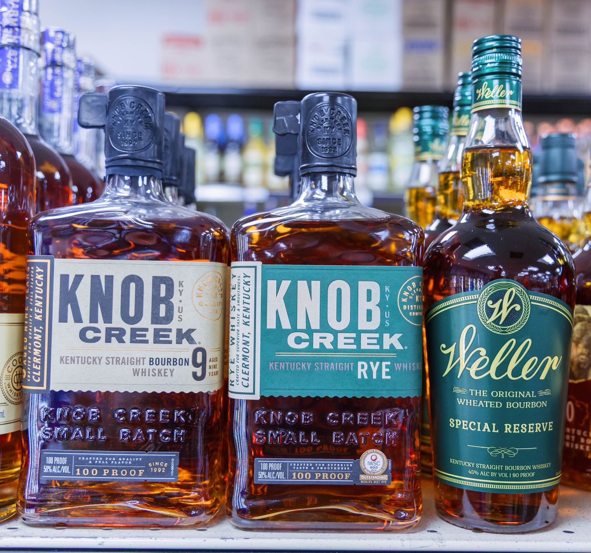 Bottles of Knob Creek whiskey and Weller Special Reserve bourbon on a shelf.