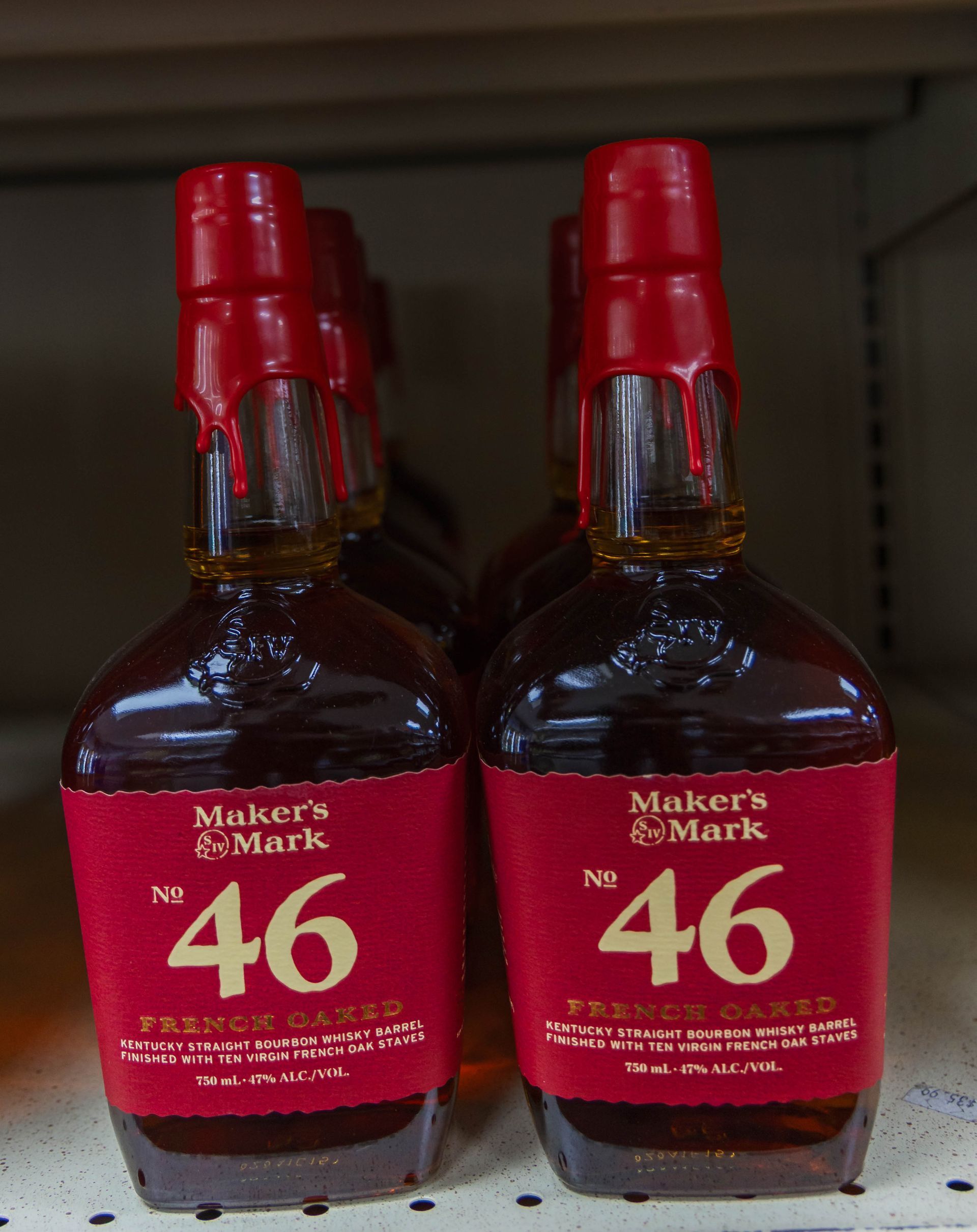 Bottles of Maker's Mark 46 bourbon with red labels and wax seals on a store shelf.