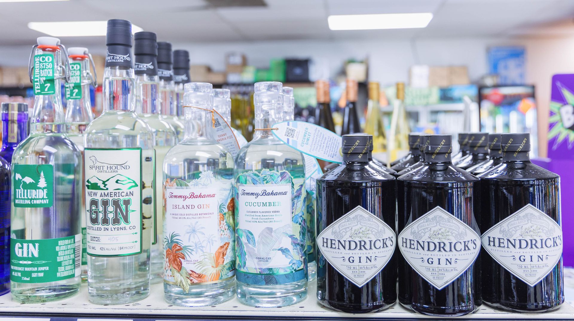 Bottles of gin on a store shelf. Some are clear, some dark. Brands include Hendrick's and Tommy Bahama.