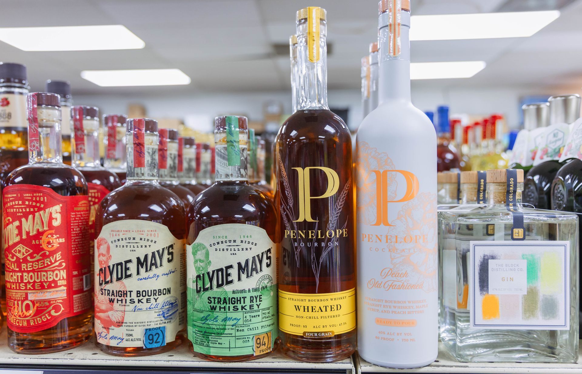 Bottles of liquor on a store shelf. Includes Clyde May's whiskey in various bottles.