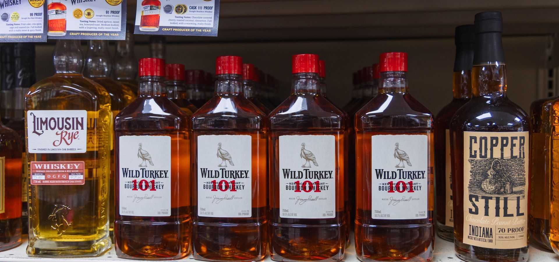 Bottles of liquor on a shelf; includes Wild Turkey 101 and Copper Still brands.