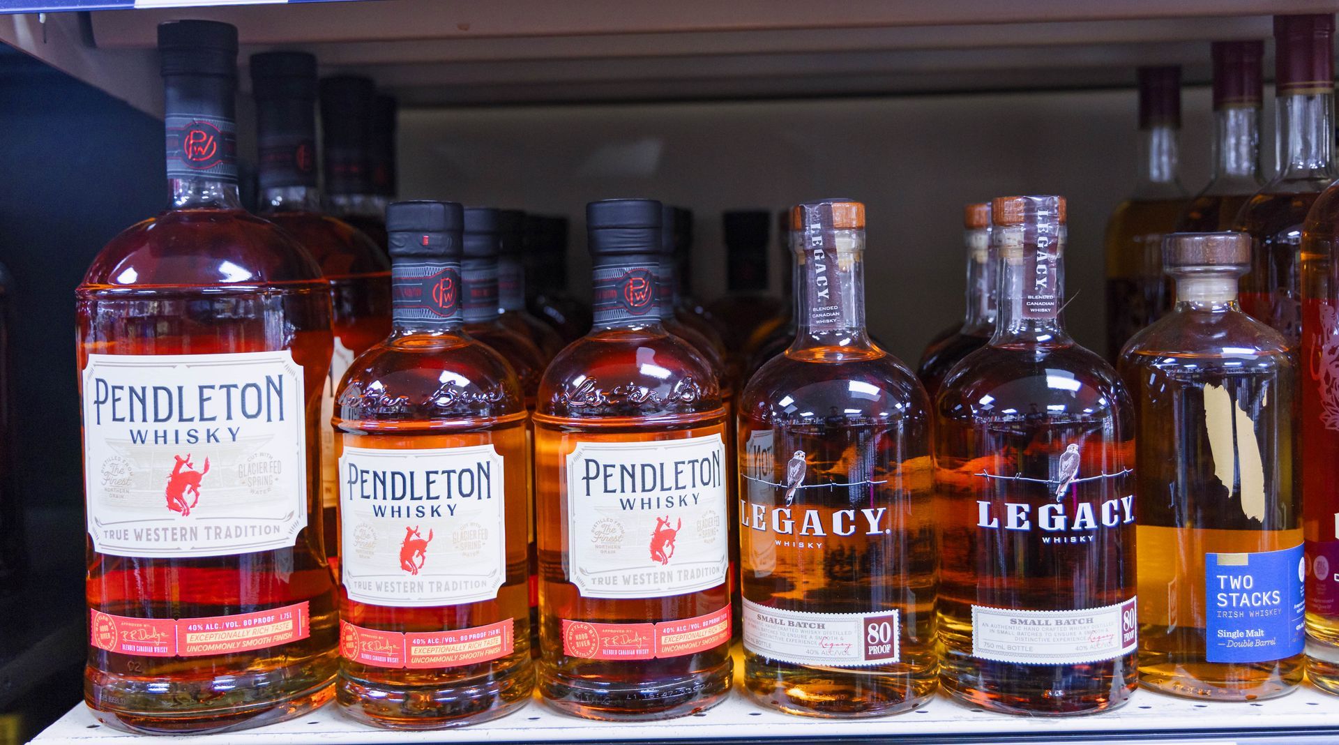 Bottles of Pendleton and Legacy whiskey on a store shelf, various sizes and labels.