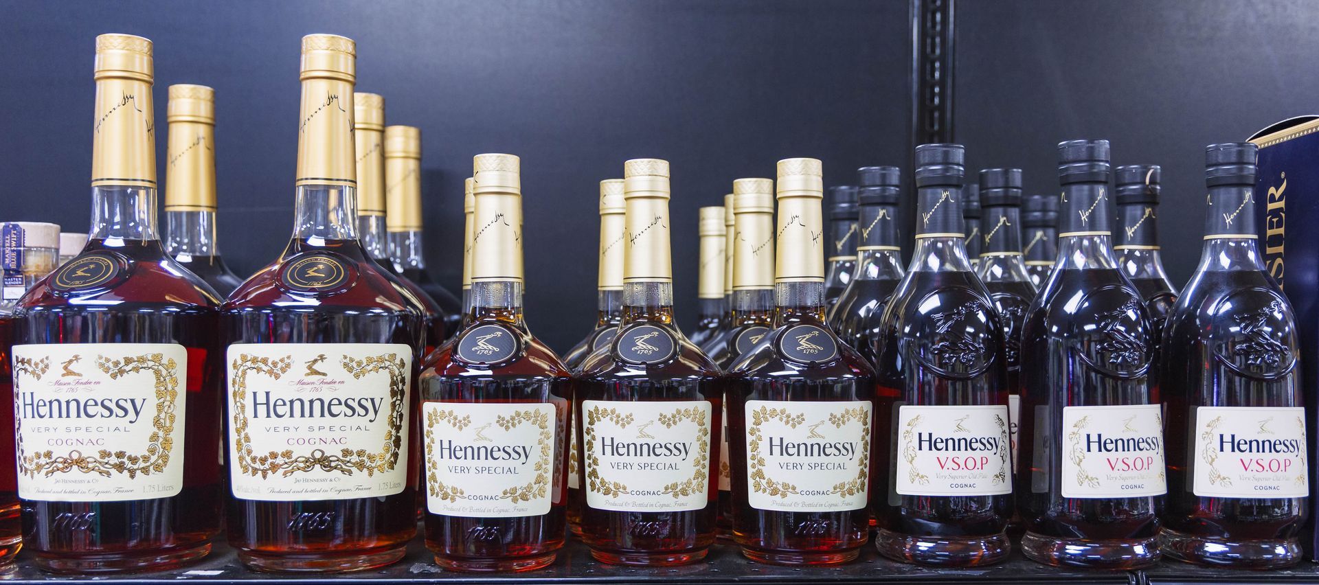 Bottles of Hennessy cognac on a shelf, with gold foil tops and cream labels.