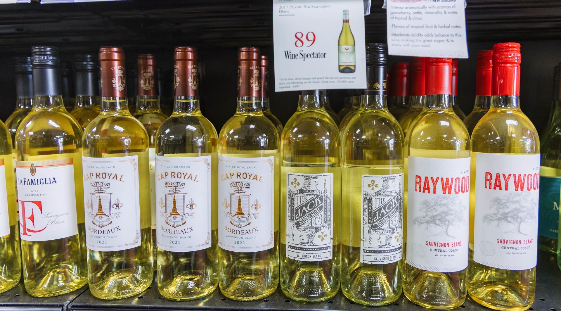 Bottles of white wine on a shelf, various labels and price tag.