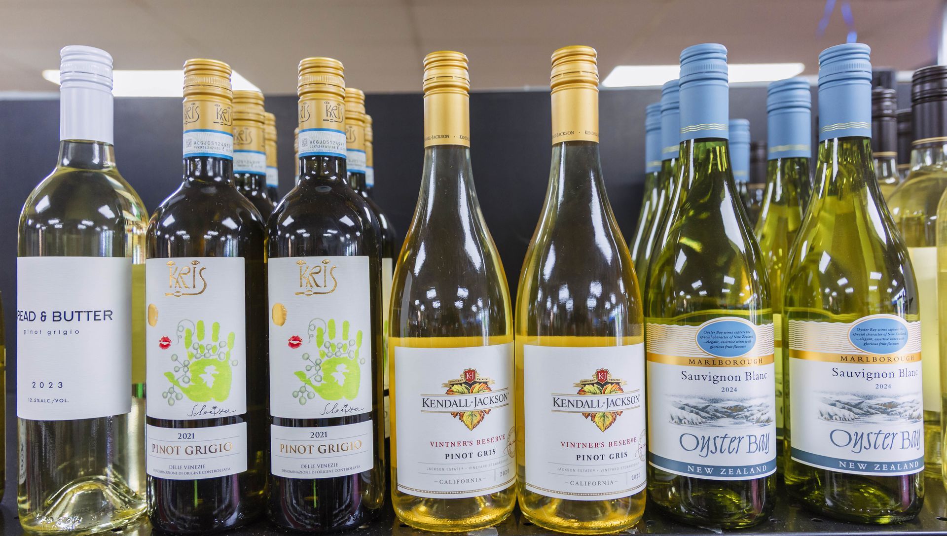 Bottles of white wine on a store shelf with various label designs, including gold and blue.