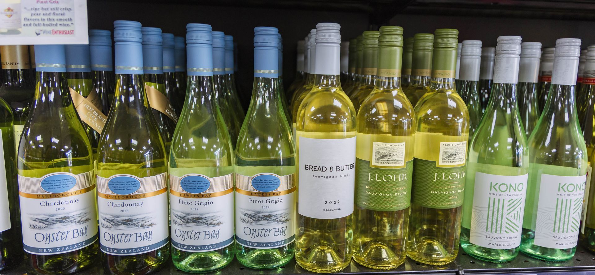 Bottles of white wine on a store shelf, with blue and white labels.