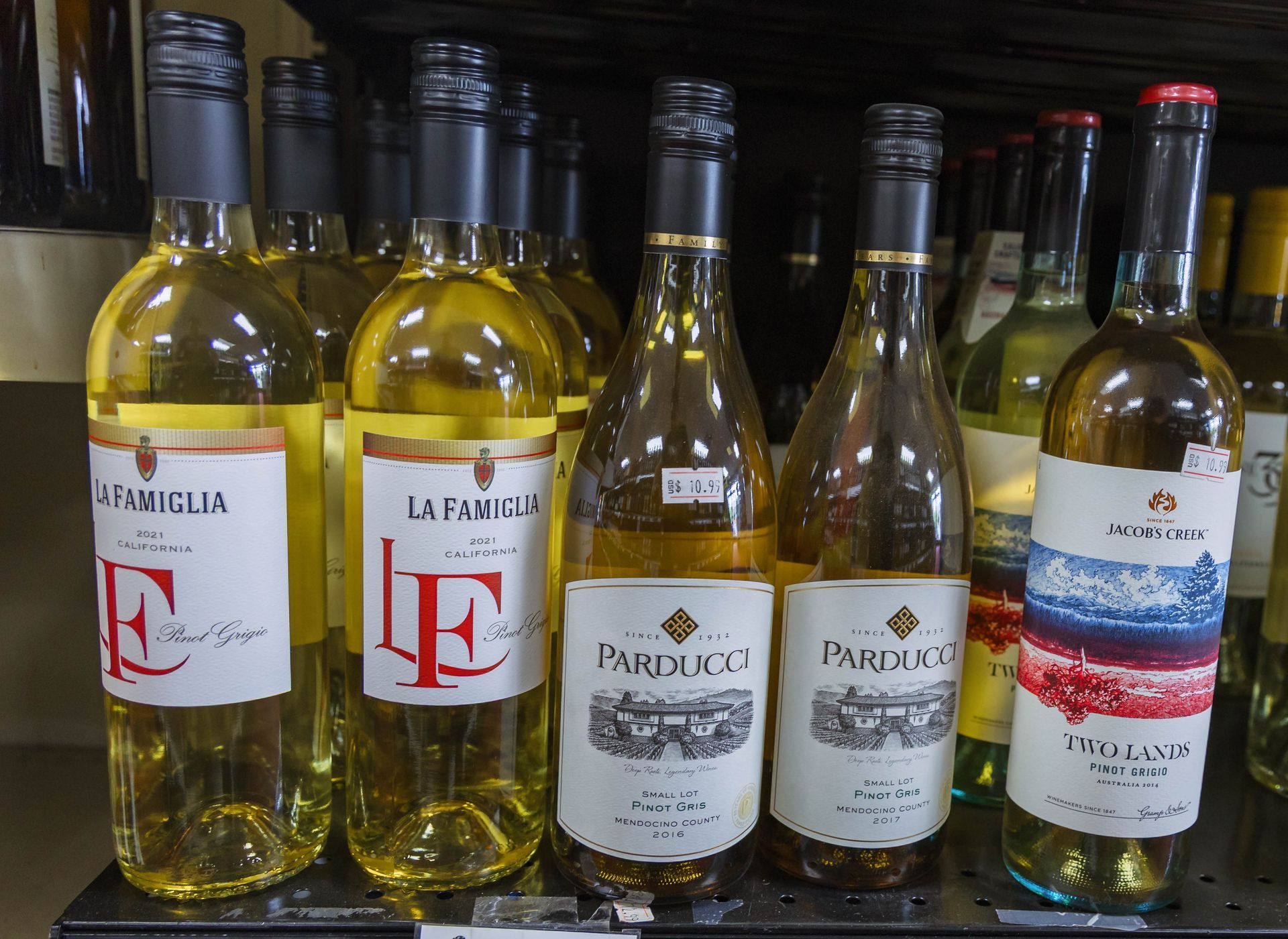 Bottles of white wine on a shelf, with labels in various designs and colors.