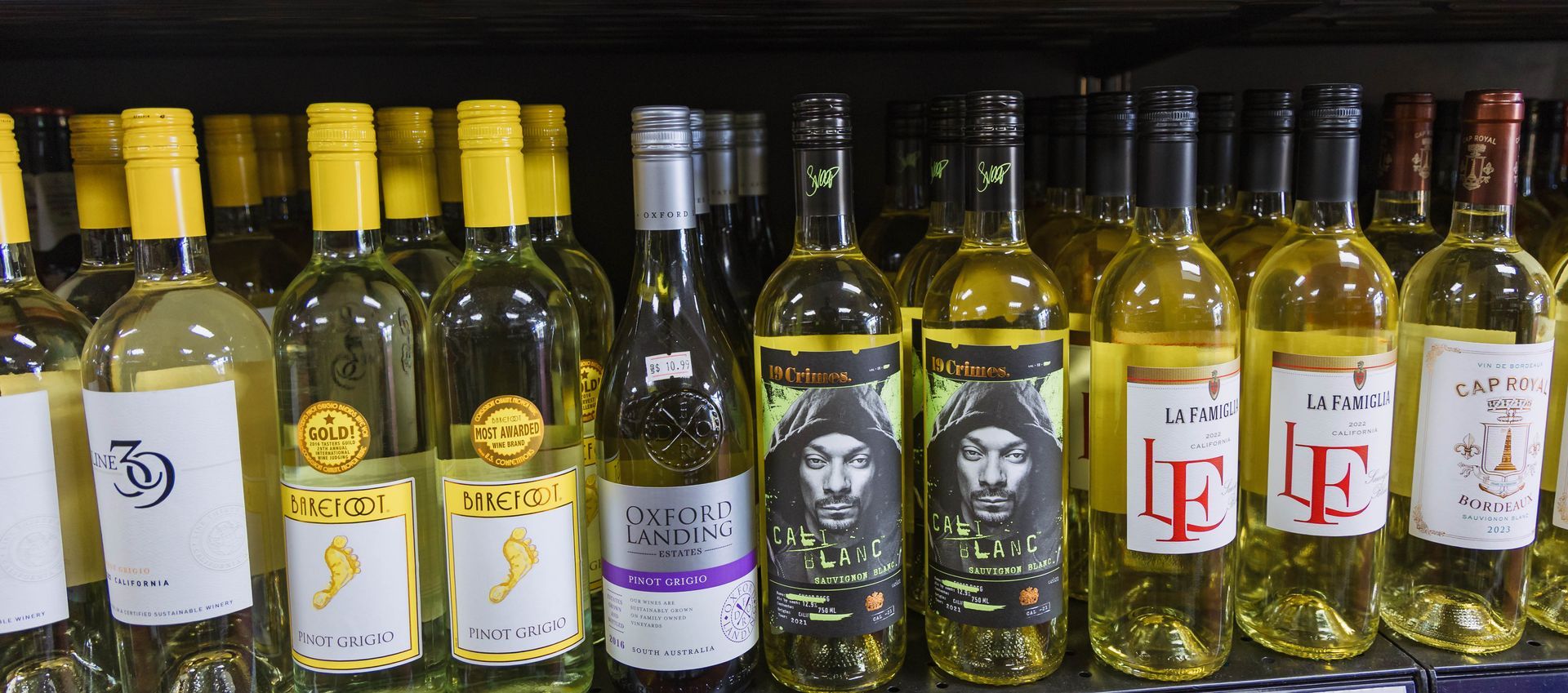 Bottles of white wine with various labels on a shelf.