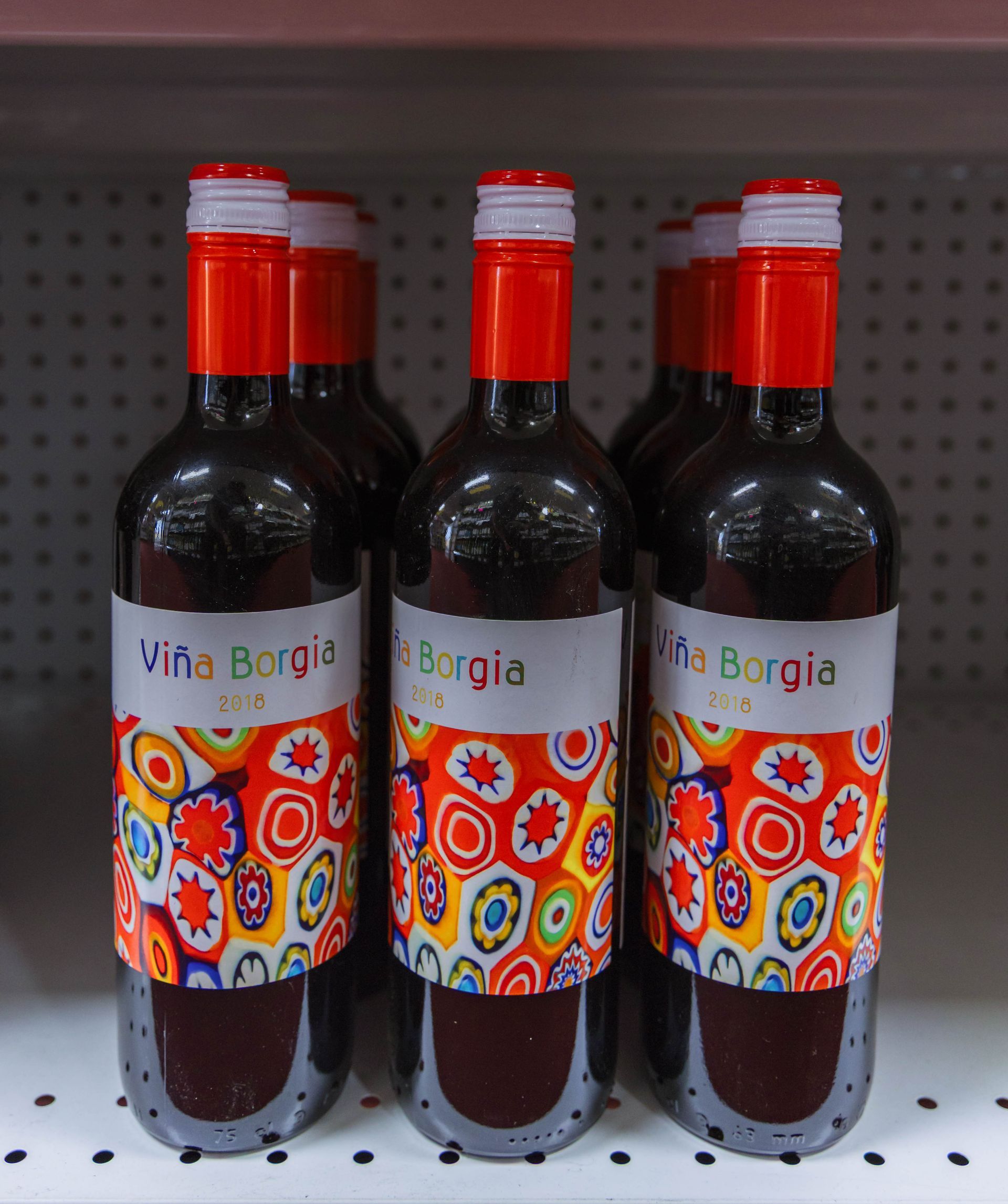 Bottles of red Viña Borgia wine with red and colorful labels on a shelf.