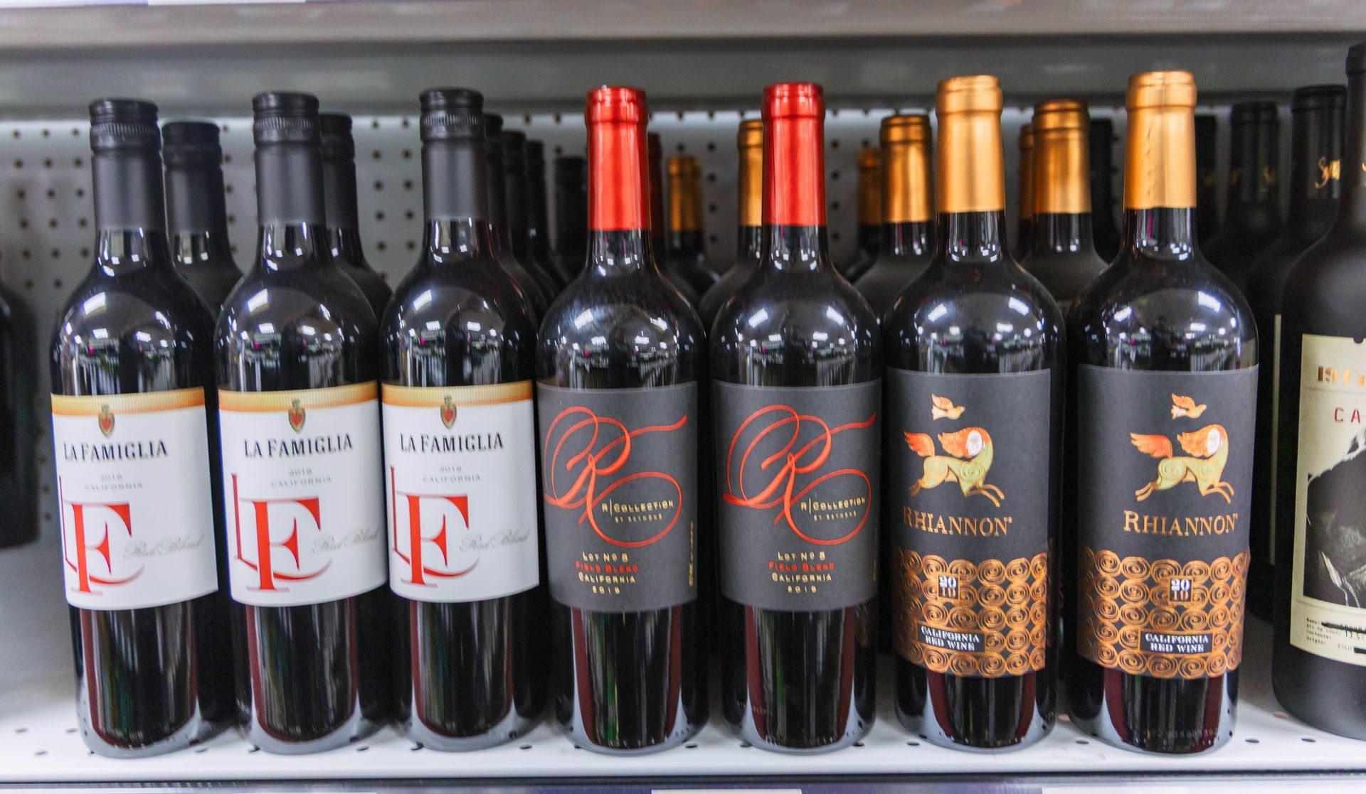 Wine bottles on a shelf with red, black, and gold labels.