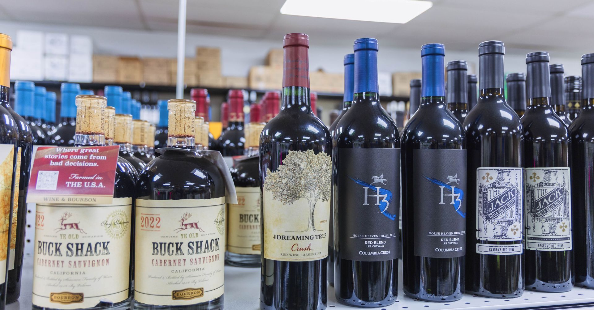 Wine bottles on a store shelf, various labels with corks.