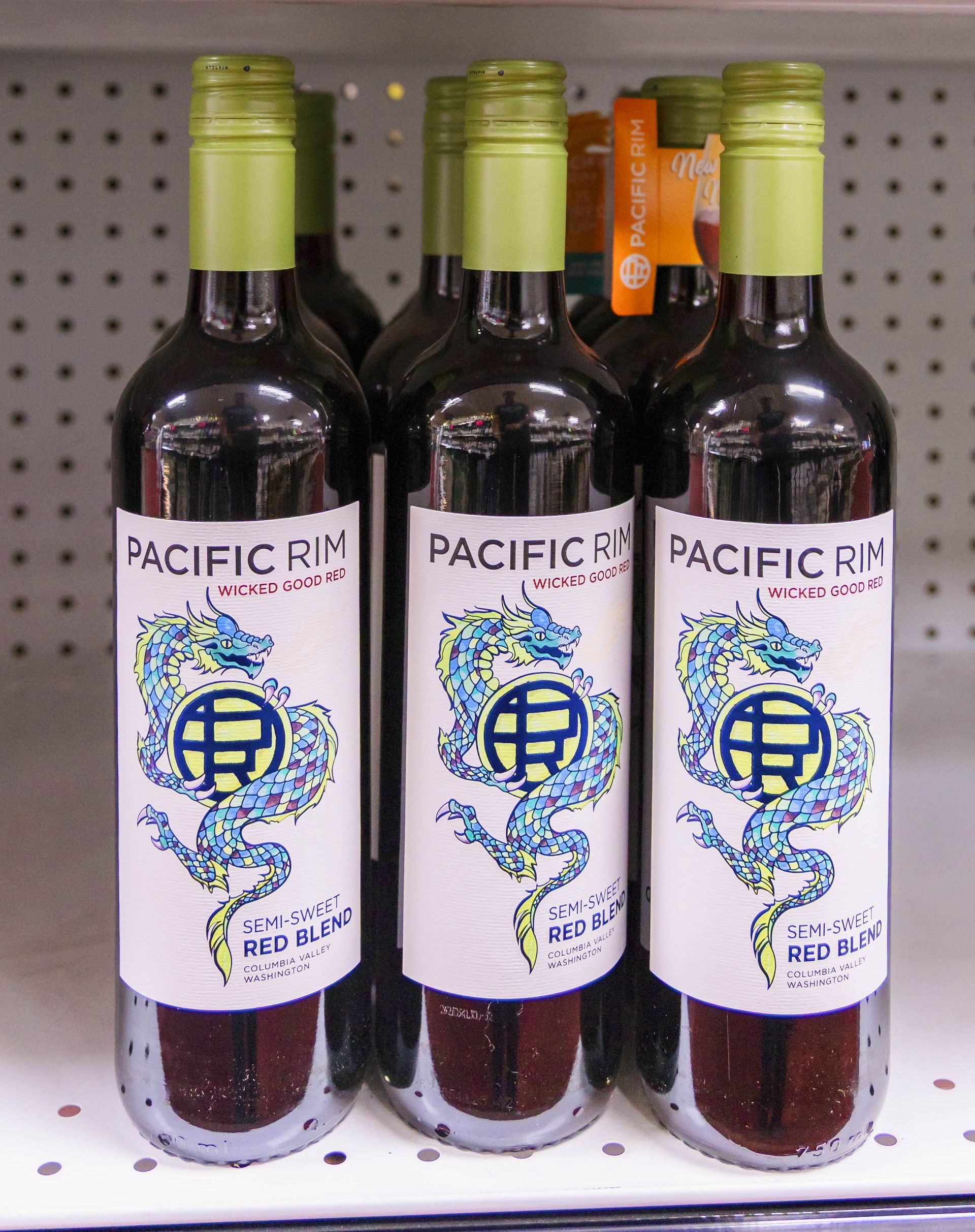 Bottles of Pacific Rim Red Blend wine with dragon label, on a store shelf.