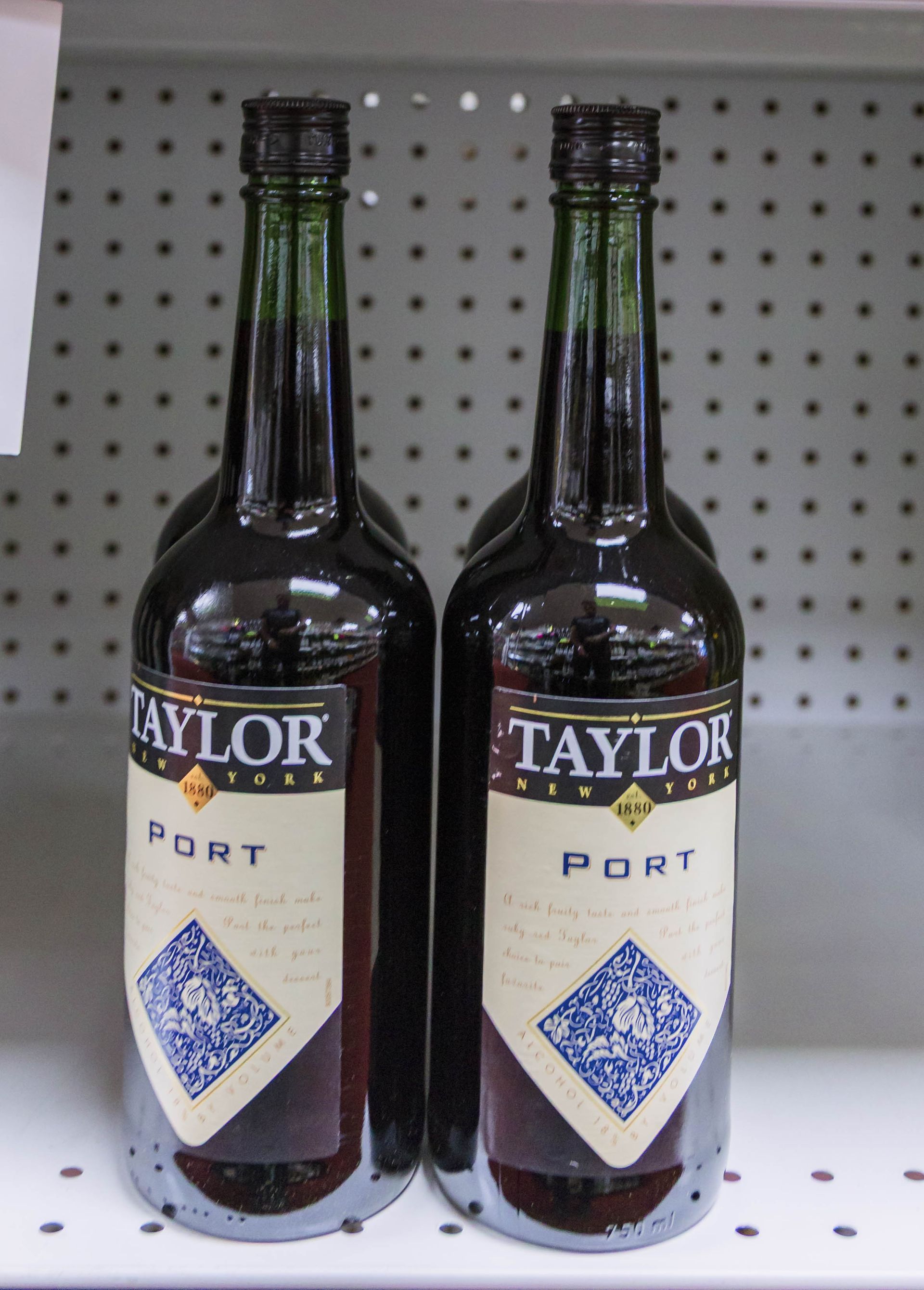 Two bottles of Taylor Port wine on a shelf with a white background.