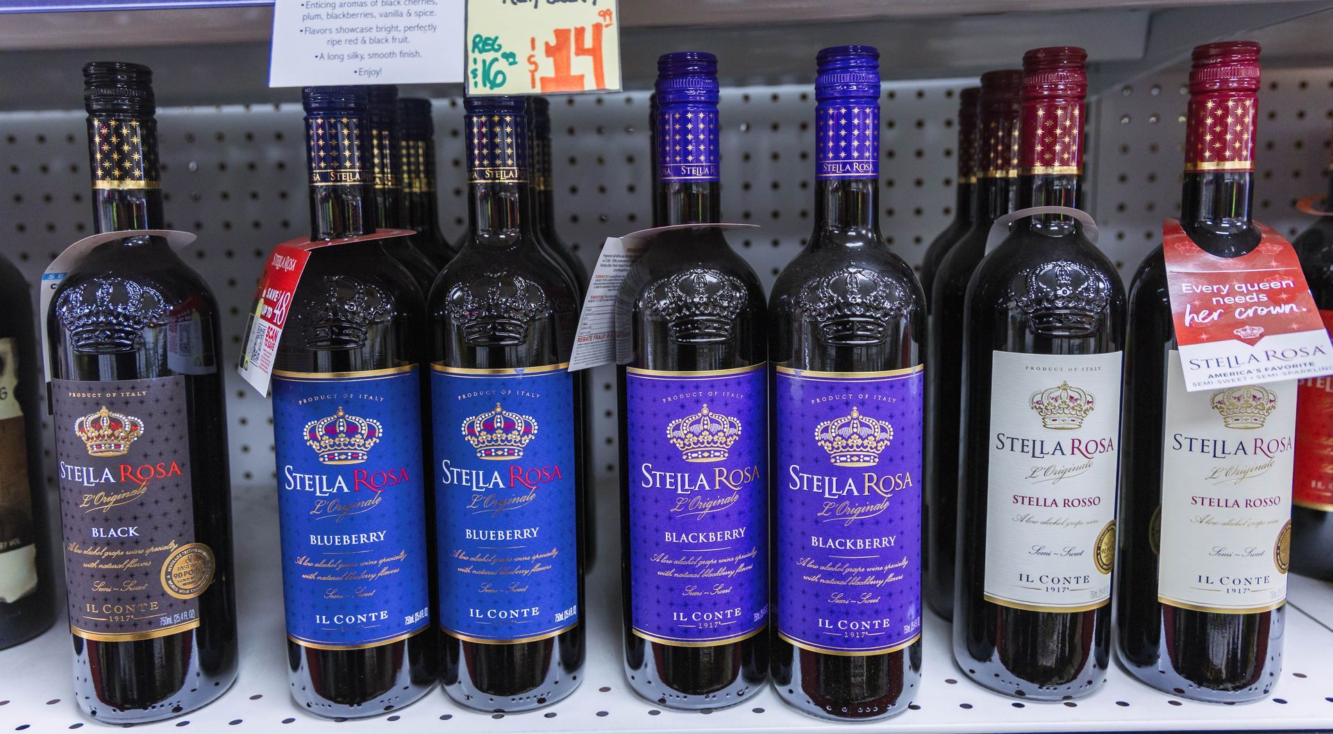 Wine bottles on a shelf, labels in blue, purple, and burgundy, in a store setting.