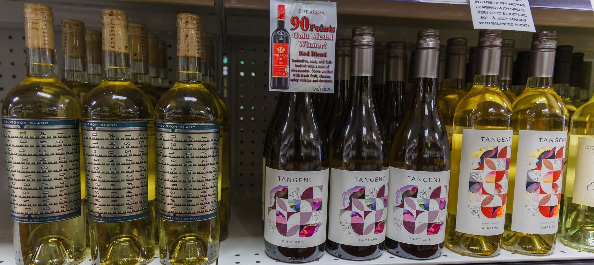 Wine bottles on a shelf, with a sign advertising a 90-point red wine.