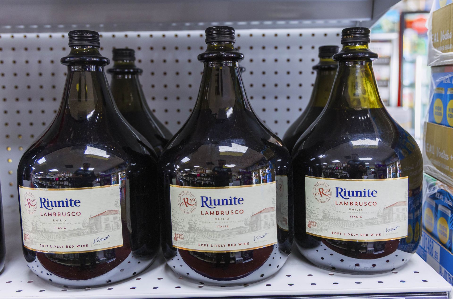 Row of large Riunite Lambrusco wine bottles on a store shelf.