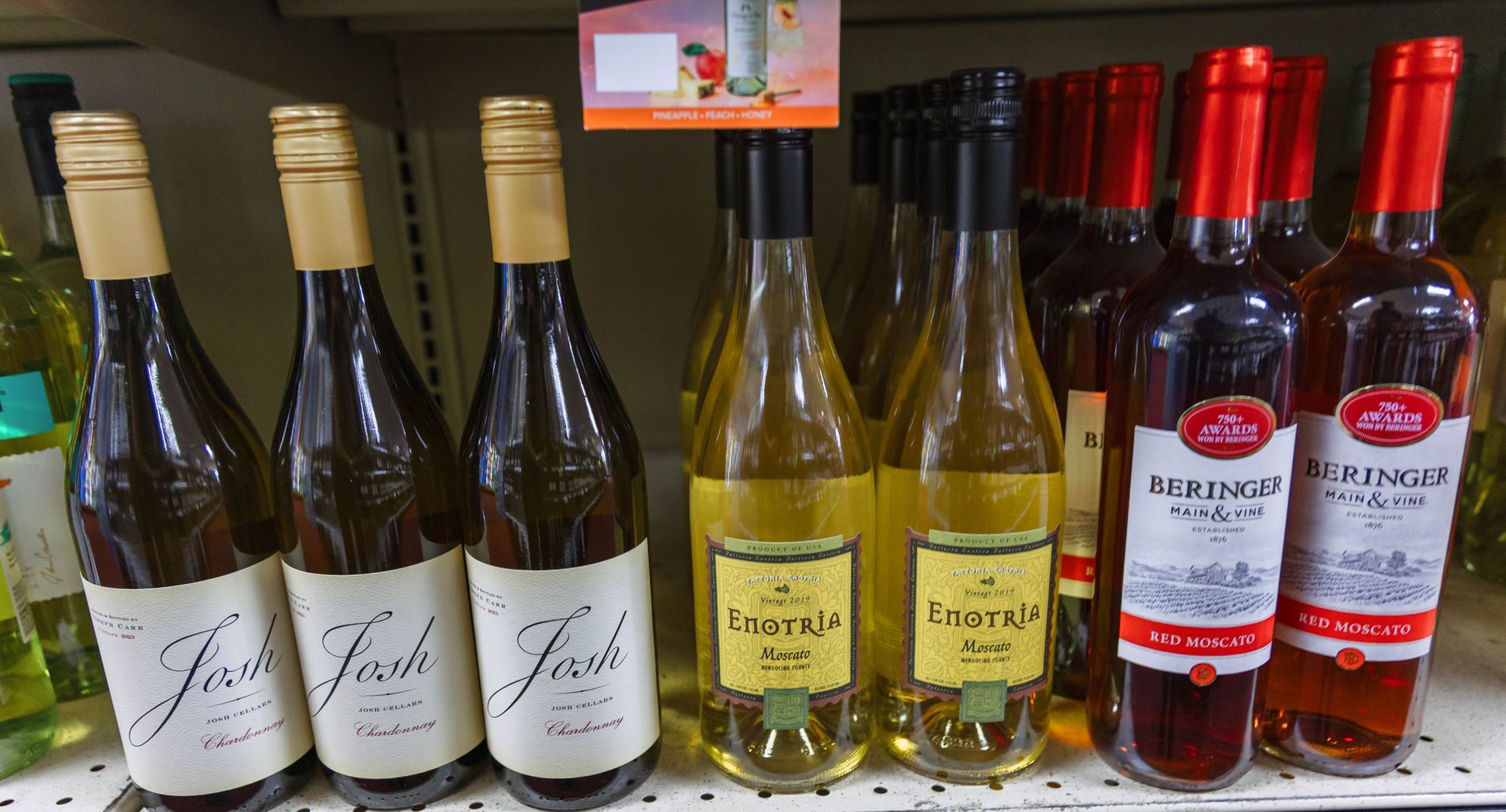 Bottles of wine on a shelf, including white, gold, and red varieties with various label designs.