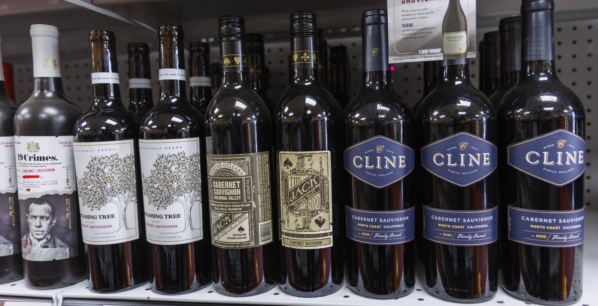 Wine bottles on a shelf. Several bottles of Cline wine are visible with navy and gold labels.