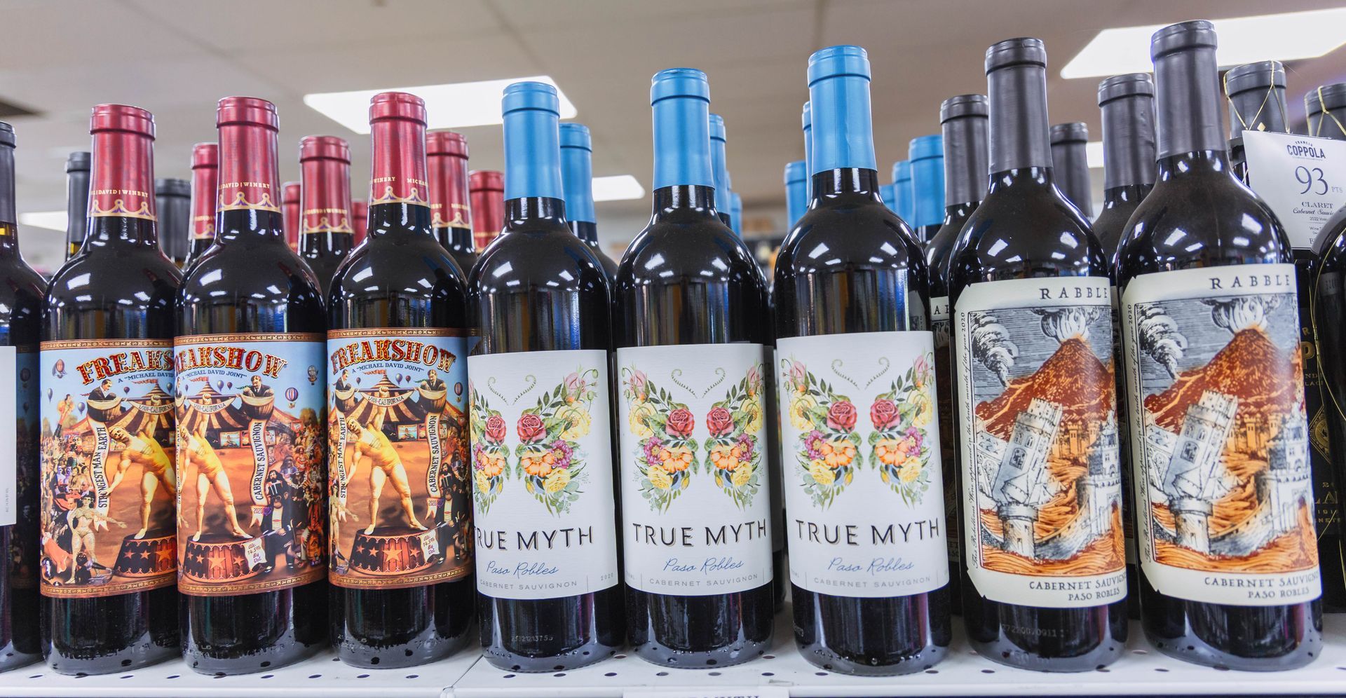 Bottles of wine on a shelf; labels feature illustrations and text.