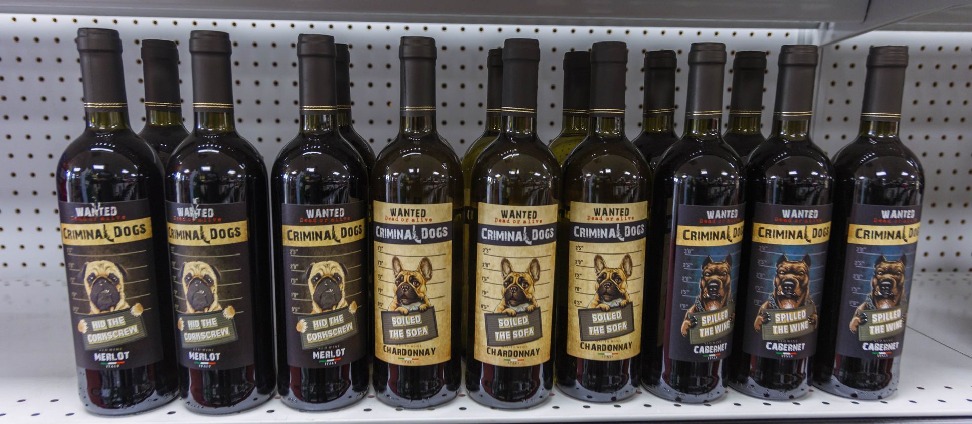 Bottles of red wine with dog illustrations on the labels. Shelf display in a store.