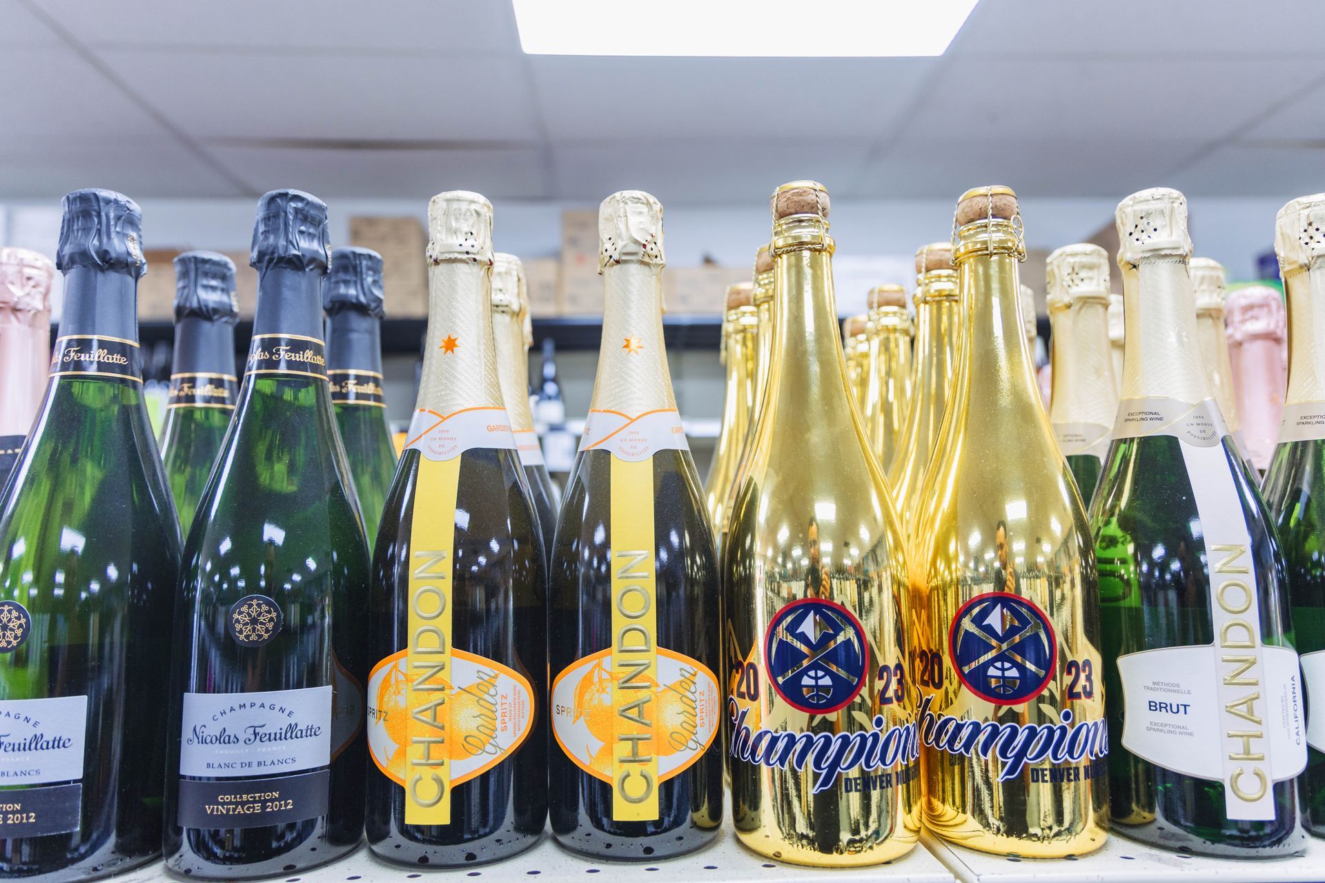 Bottles of Chandon champagne on a shelf, some gold-wrapped, others green.