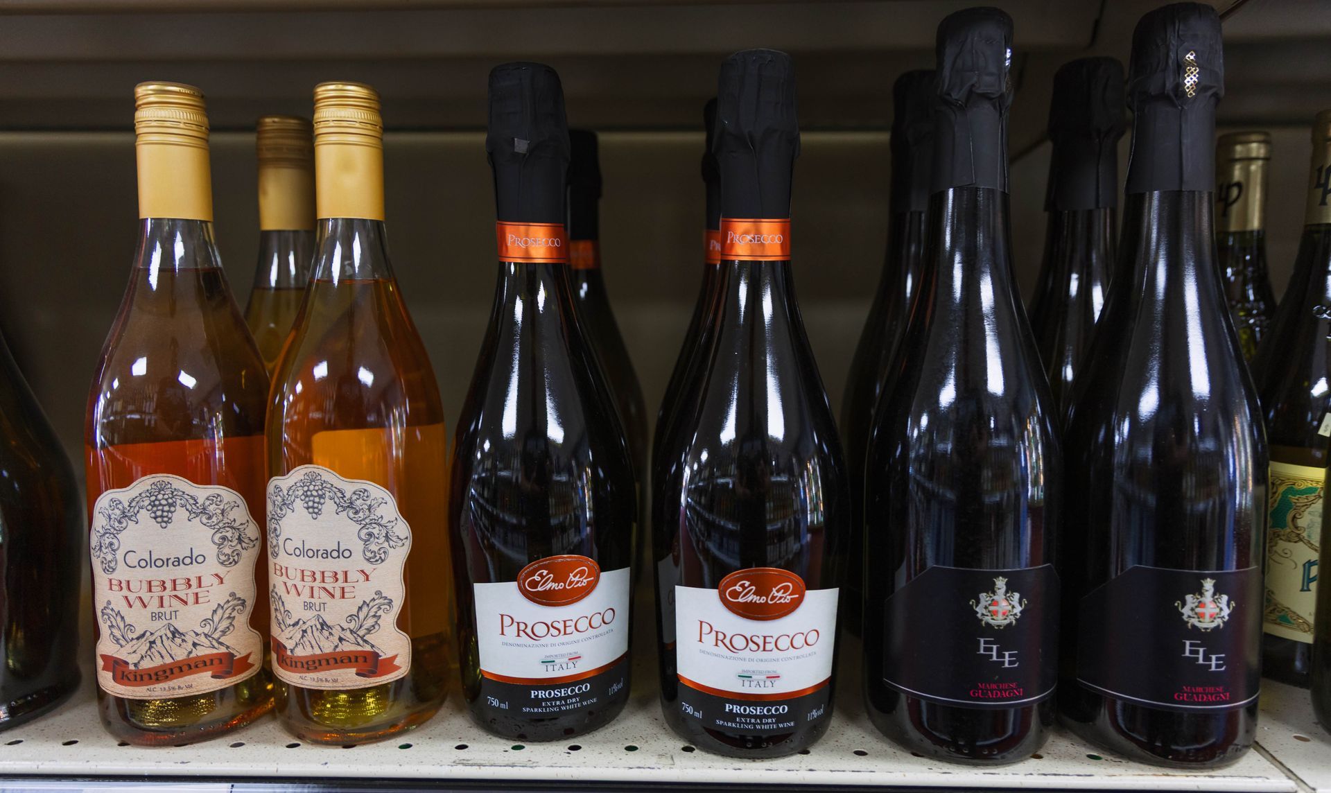 Wine bottles on a shelf, including rosé and sparkling Prosecco.