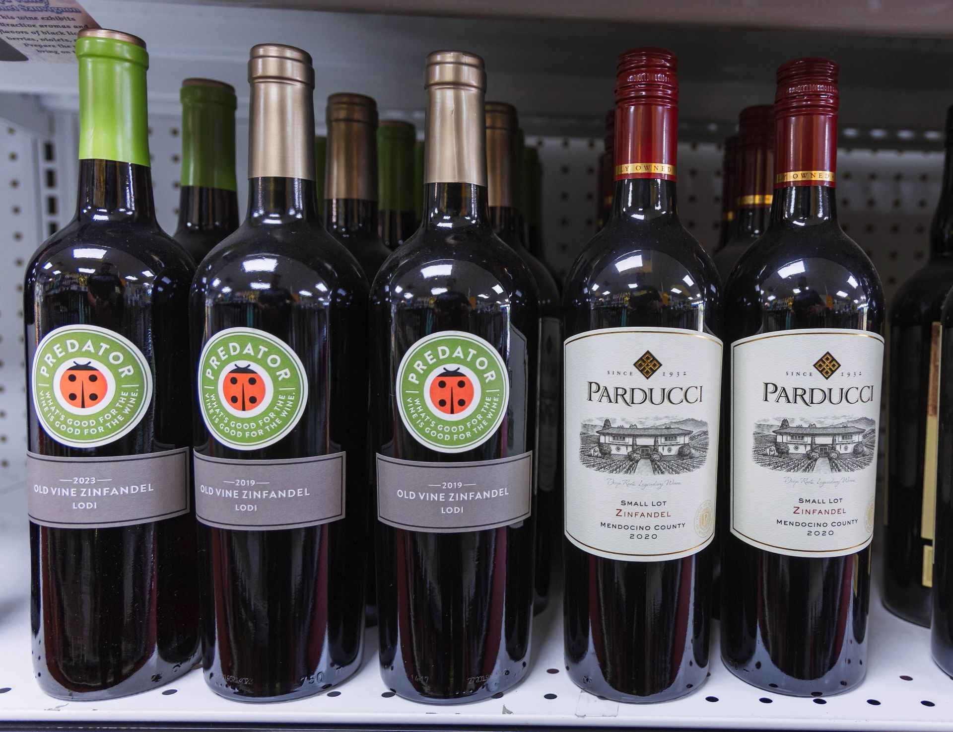 Bottles of red wine on a shelf: Predator and Parducci labels, green, tan, and red accents.