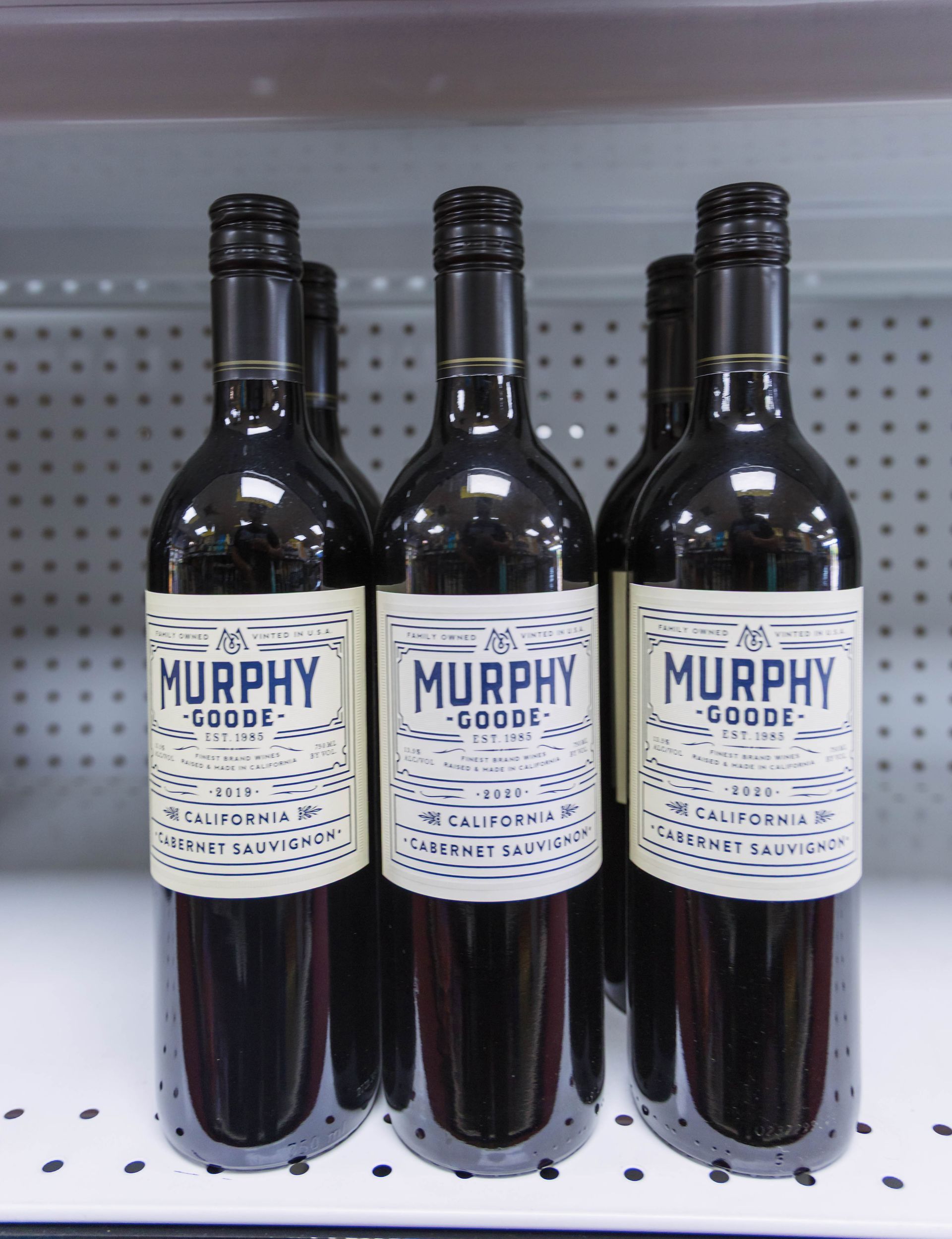 Bottles of Murphy-Goode wine on a shelf, dark glass with white labels and a red wine fill.