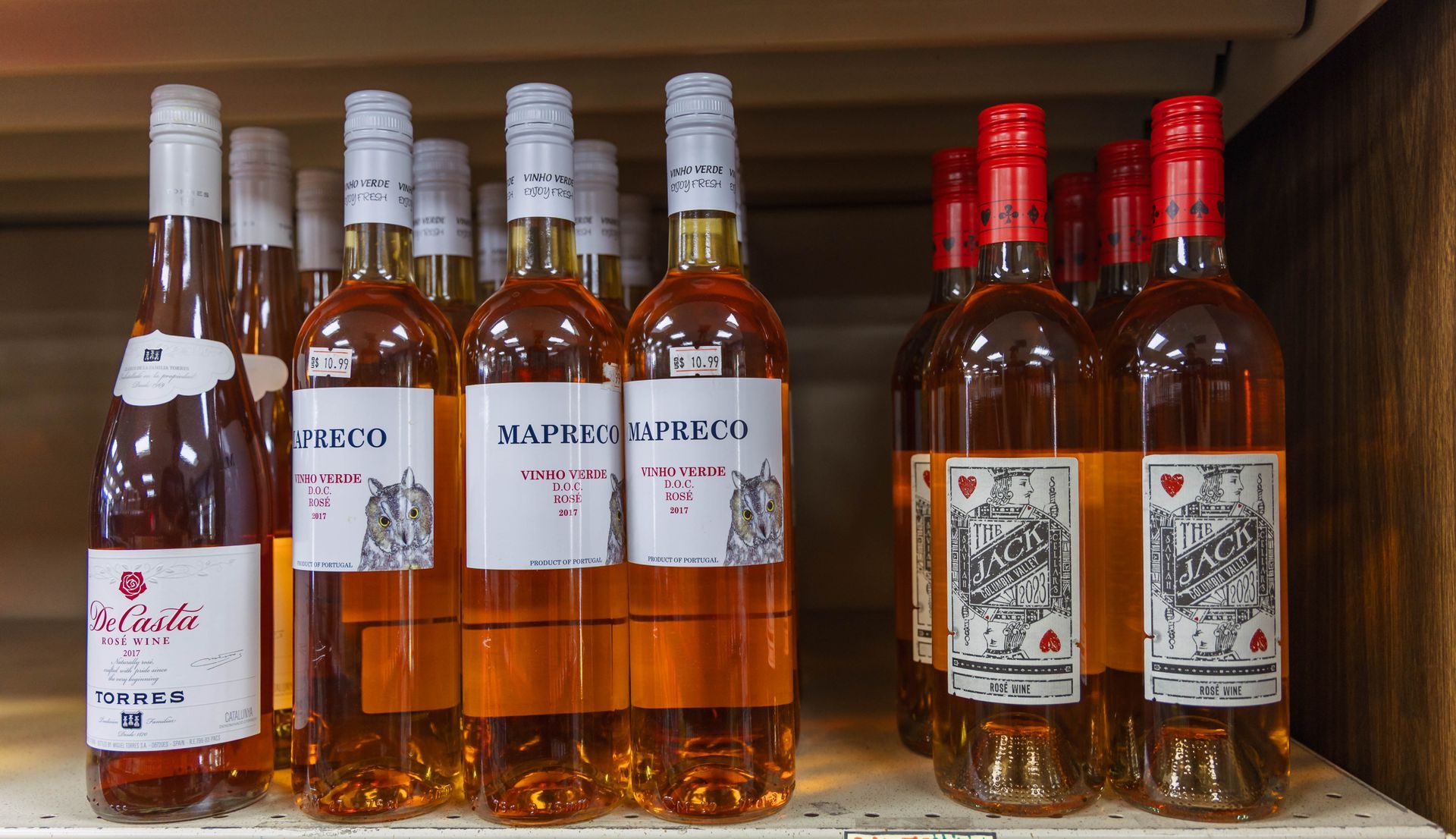 Bottles of rosé wine on a shelf, labels with text and illustrations.