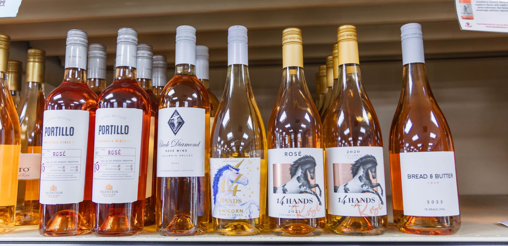 Bottles of rosé wine on a shelf, with labels displaying various images and text.