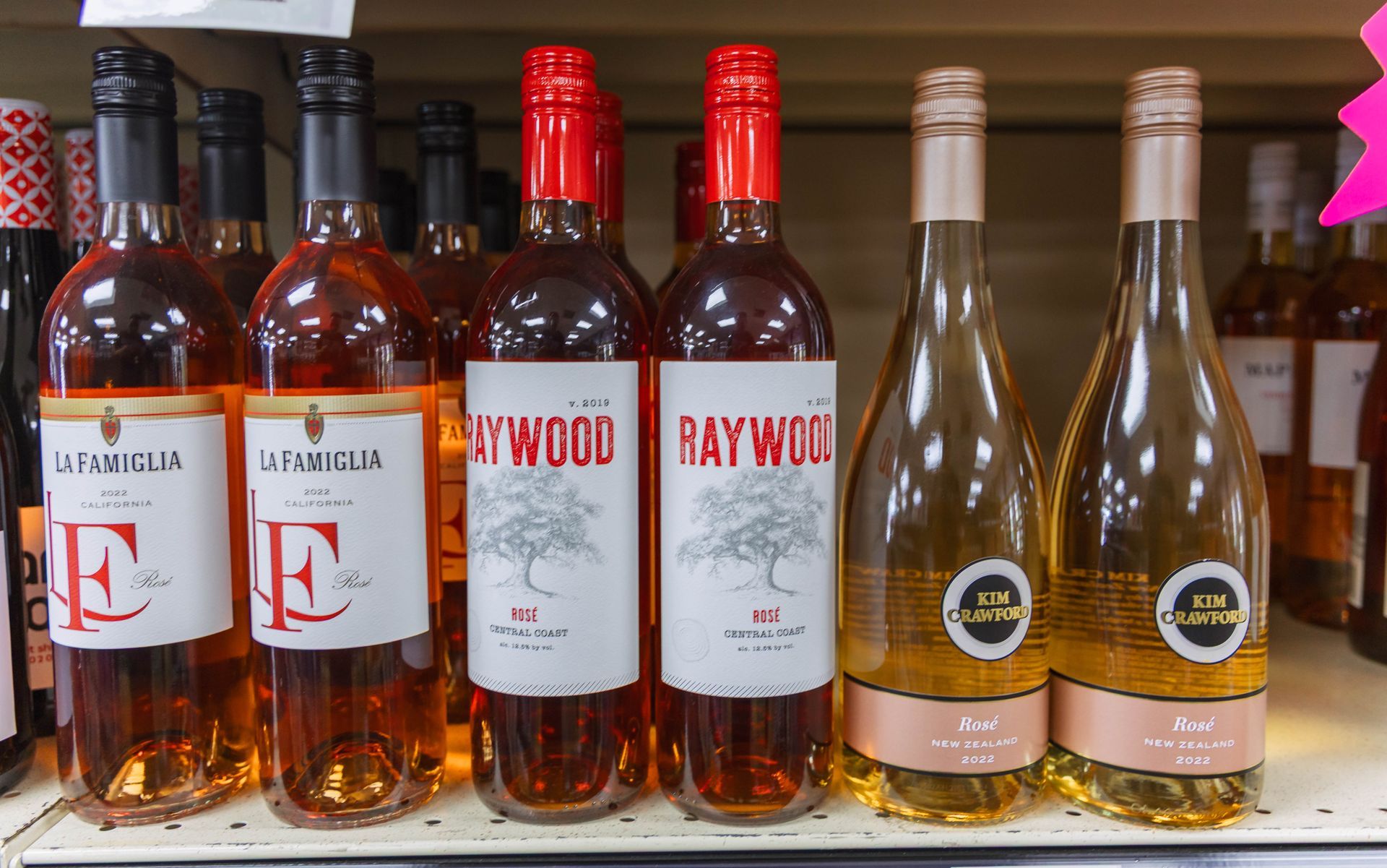 Wine bottles of various brands and colors on a shelf.