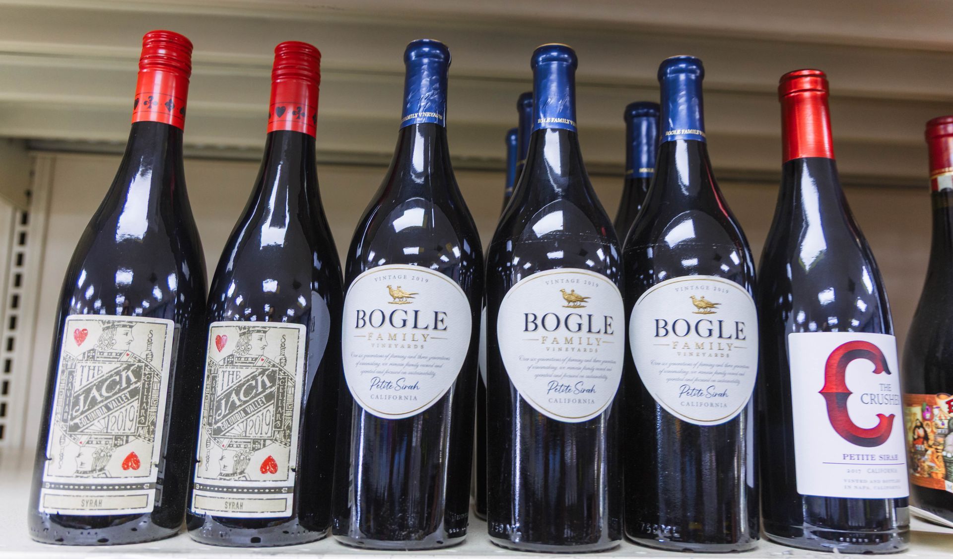 Bottles of wine with red and blue bottle caps, displayed on a shelf. Bogle brand wine prominent.